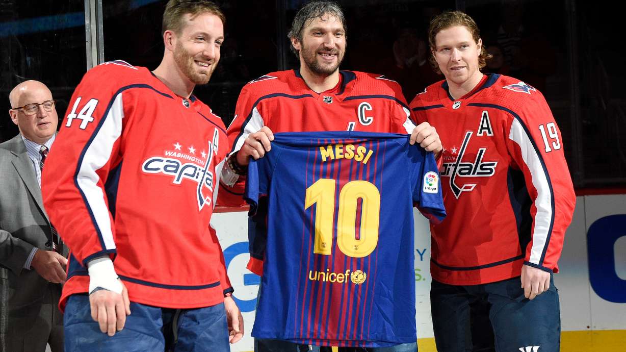FILE - Washington Capitals left wing Alex Ovechkin, center, of Russia, poses with a Messi soccer jersey with Nicklas Backstrom (19), of Sweden, and Brooks Orpik (44) during a ceremony in honor of his 1,000th NHL hockey game, before the team's game against the Nashville Predators on Thursday, April 5, 2018, in Washington. The happiest professional athlete outside soccer about Lionel Messi winning the World Cup might be hockey star Alex Ovechkin.