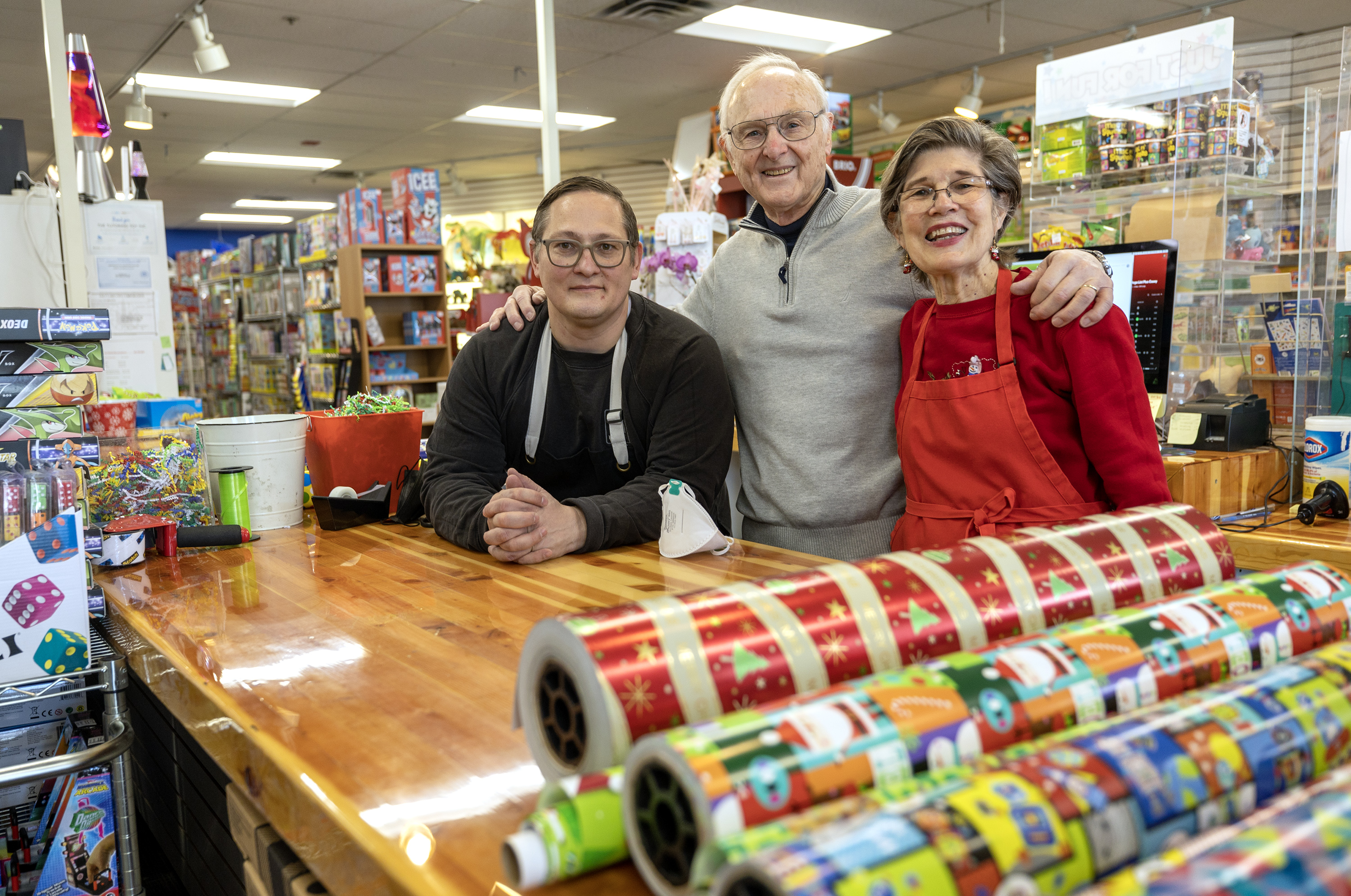 Bill Sartain, center, his wife Diane and their son Casey pose for photos at work in their toy store, the Tutoring Toy, in Salt Lake City on Monday.