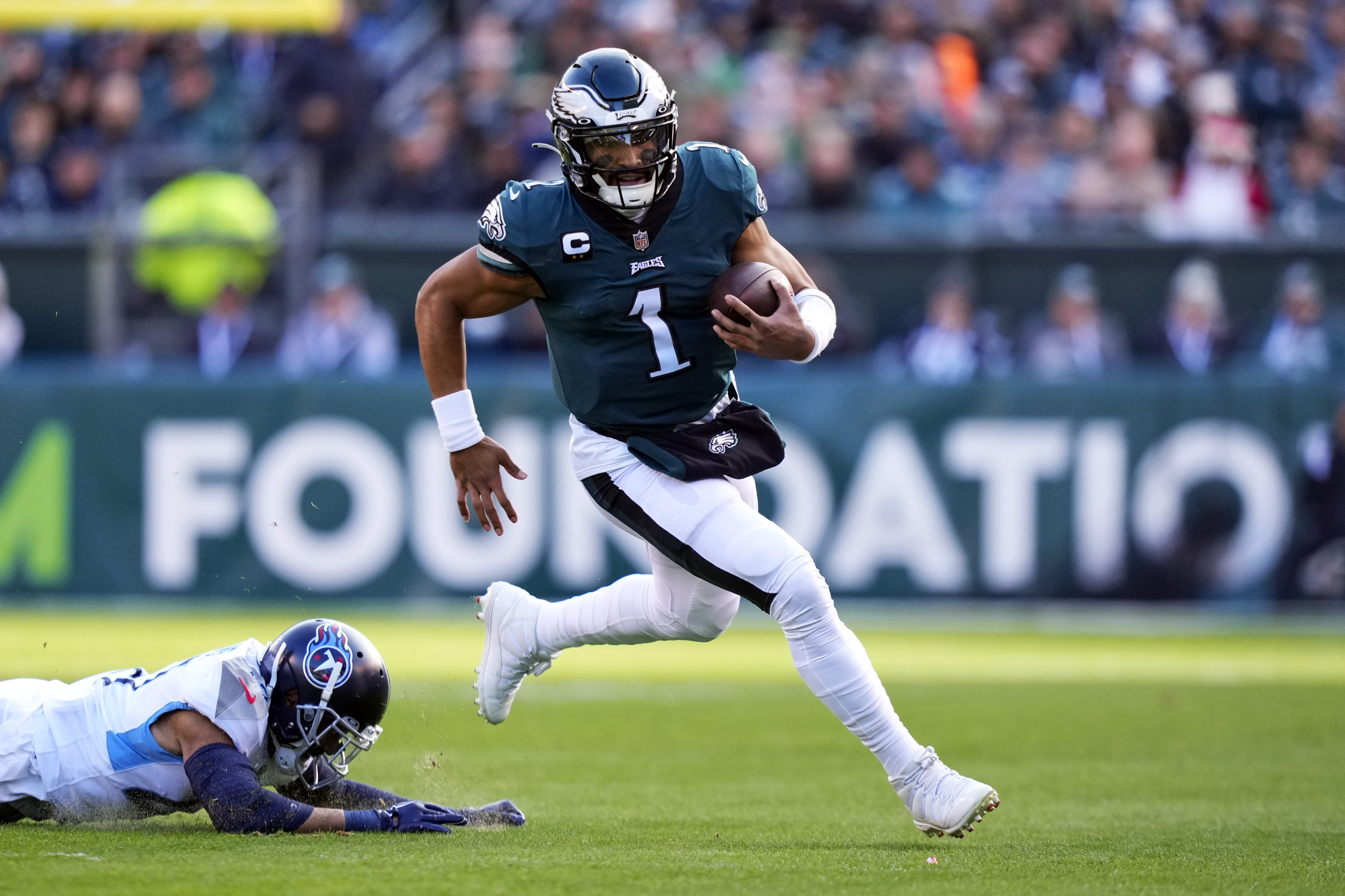 Philadelphia Eagles' Jalen Hurts runs past Tennessee Titans' Andrew Adams during the first half of an NFL football game, Sunday, Dec. 4, 2022, in Philadelphia. 