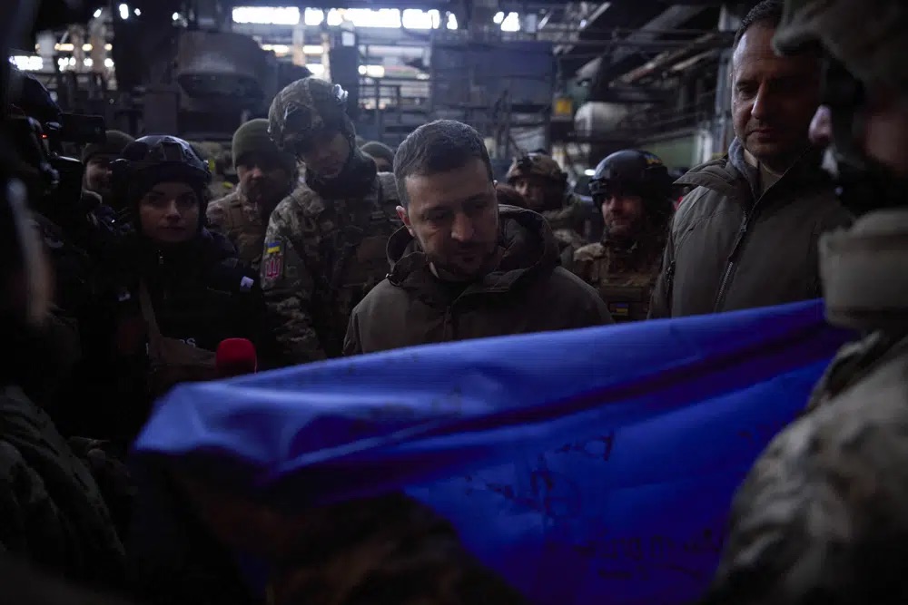 Ukrainian President Volodymyr Zelenskyy signs a Ukraine national flag at the site of the heaviest battles with the Russian invaders in Bakhmut, Ukraine, Tuesday.