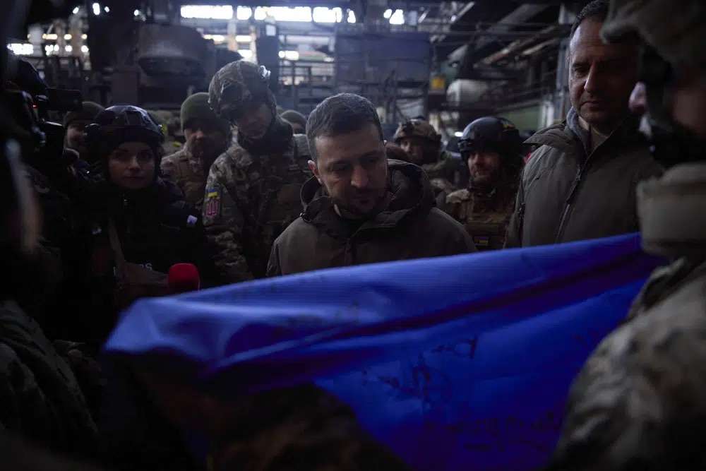 Ukrainian President Volodymyr Zelenskyy signs a Ukraine national flag at the site of the heaviest battles with the Russian invaders in Bakhmut, Ukraine, Tuesday.