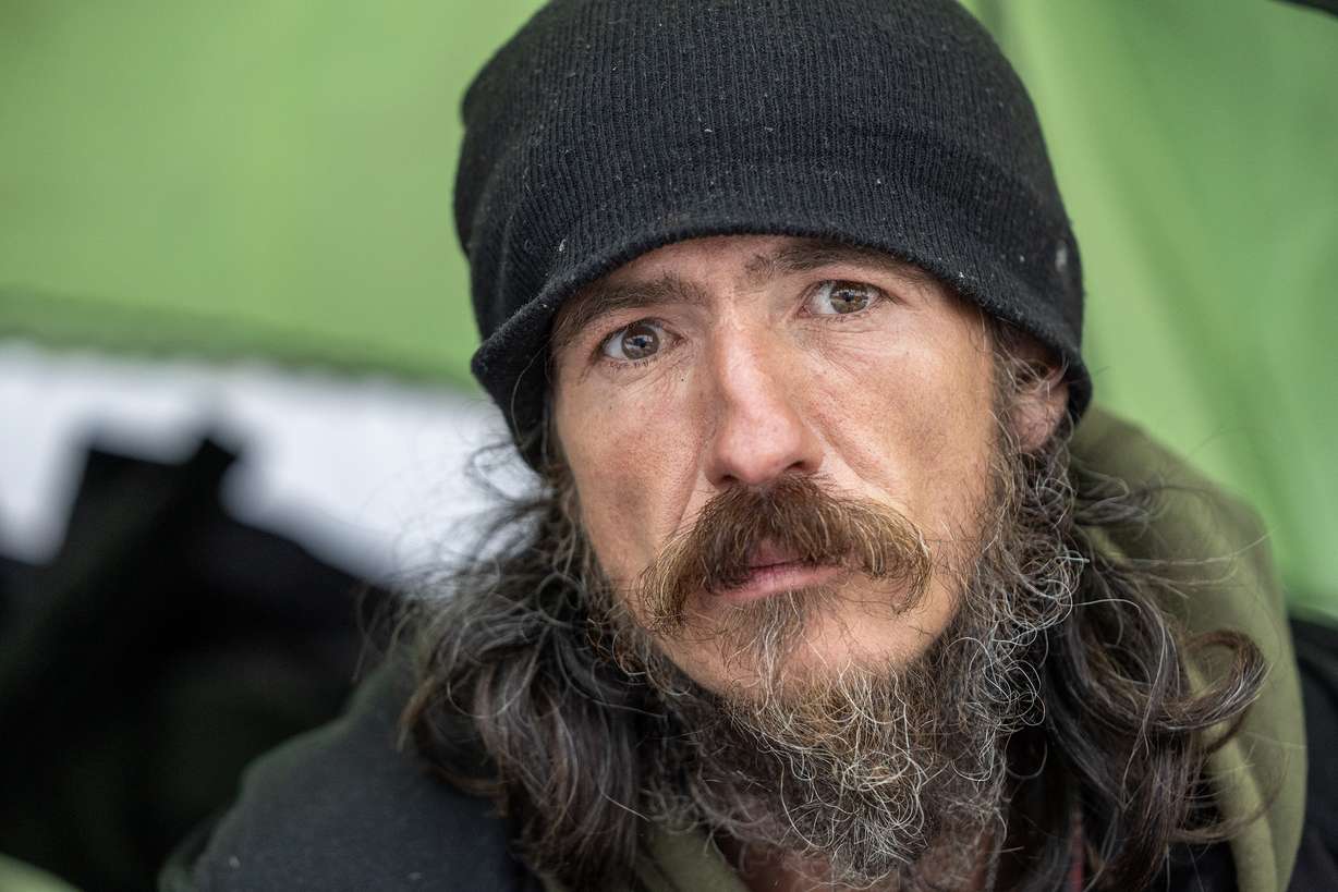 Robert Arguelles poses for a photo as he sits in the door of his tent in Salt Lake City. Five unsheltered people have died on Salt Lake streets over the past couple of days amid freezing temperatures, prompting an emergency declaration by Salt Lake City's mayor.