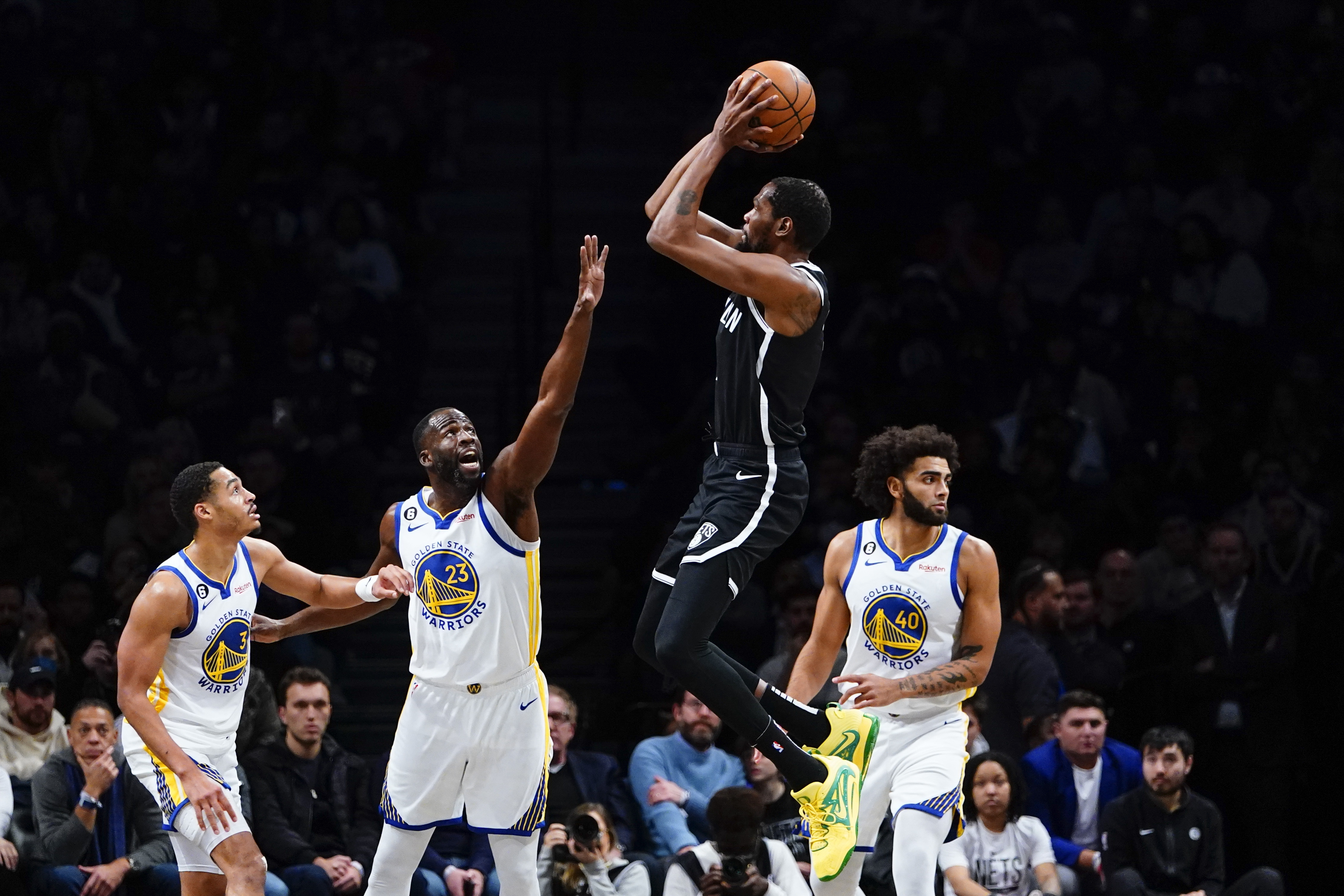 Golden State Warriors' Draymond Green (23) and Jordan Poole (3) defend a shot by Brooklyn Nets' Kevin Durant (7) during the first half of an NBA basketball game as teammate Anthony Lamb (40) watches Wednesday, Dec. 21, 2022 in New York.