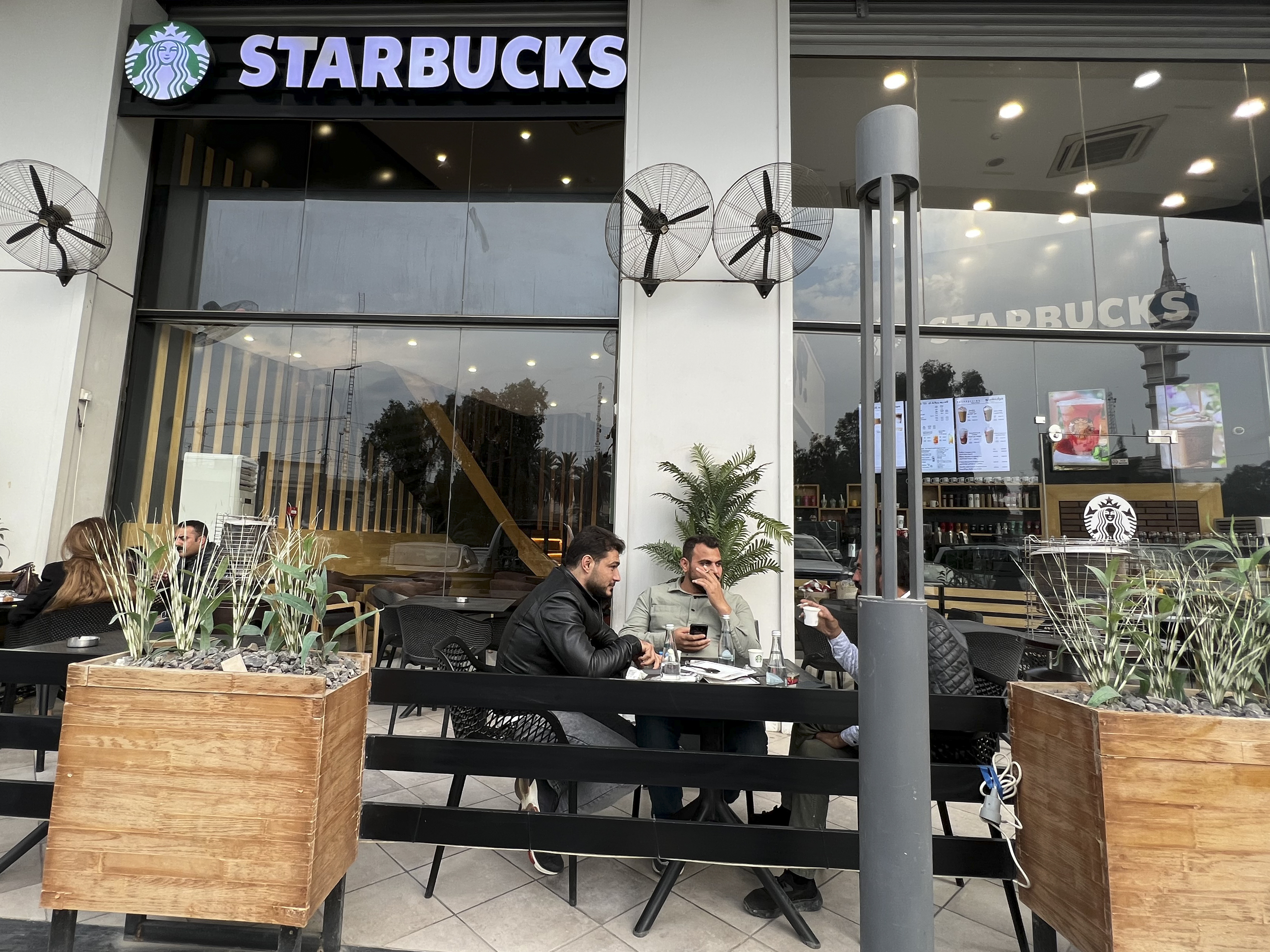 People sit in an unlicensed Starbucks cafe in Baghdad, Iraq, Wednesday. Starbucks filed a lawsuit in an attempt to shut down the trademark violation but the case was shuttered after the owner allegedly threatened lawyers hired by the coffee house. 