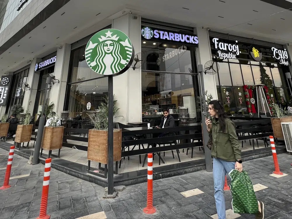 A woman walks by an unlicensed Starbucks cafe in Baghdad, Iraq, Wednesday. Real Starbucks merchandise is imported from neighboring countries to stock the three cafes in the city, but all are unlicensed. Starbucks filed a lawsuit in an attempt to shut down the trademark violation but the case was shuttered after the owner allegedly threatened lawyers hired by the coffee house.