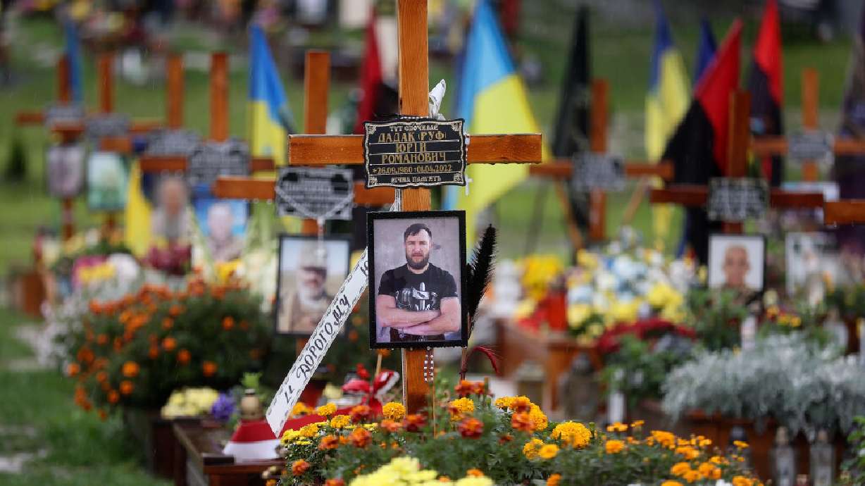 Graves of Ukrainian soldiers killed during the war with Russia are decorated with flowers, flags and photos in an overflow area just outside the fence of the historic Lychakiv Cemetery in Lviv, Ukraine, on Sept. 18. In Mariupol, Russian soldiers, builders, administrators and doctors are replacing the thousands of Ukrainians who have died or left.