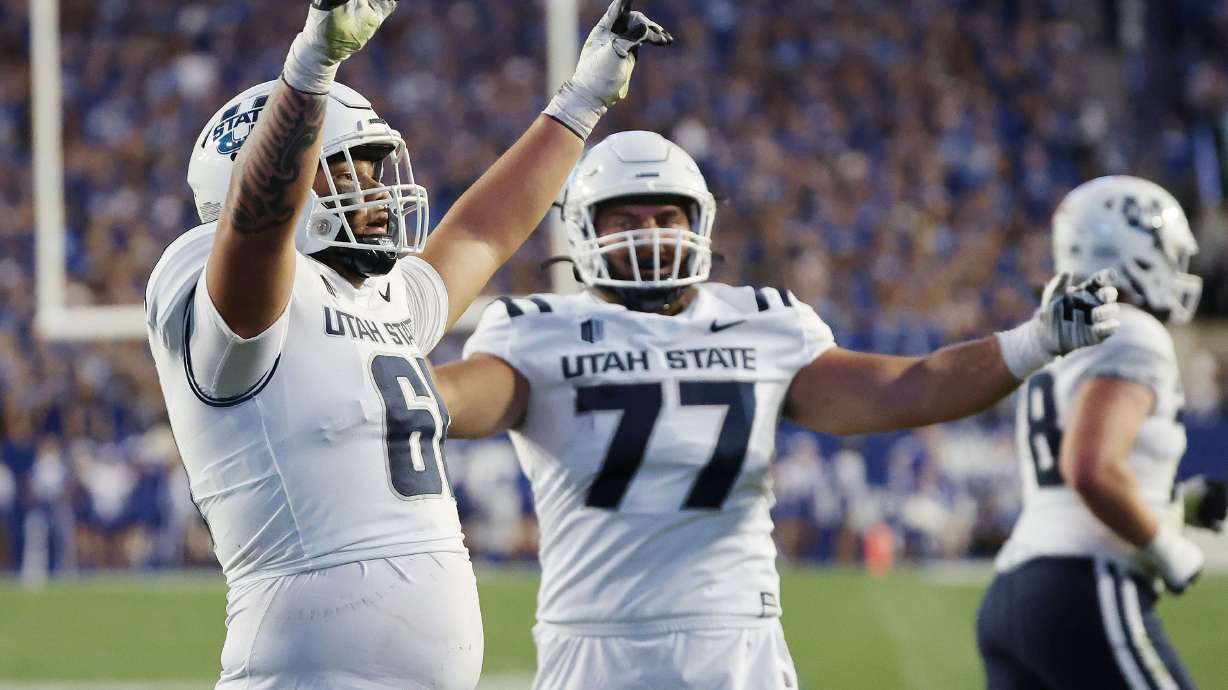 Utah State Aggies offensive lineman Weylin Lapuaho (61) and Utah State Aggies offensive lineman Calvin Knapp (77) celebrate a touchdown in Provo on Thursday, Sept. 29, 2022.