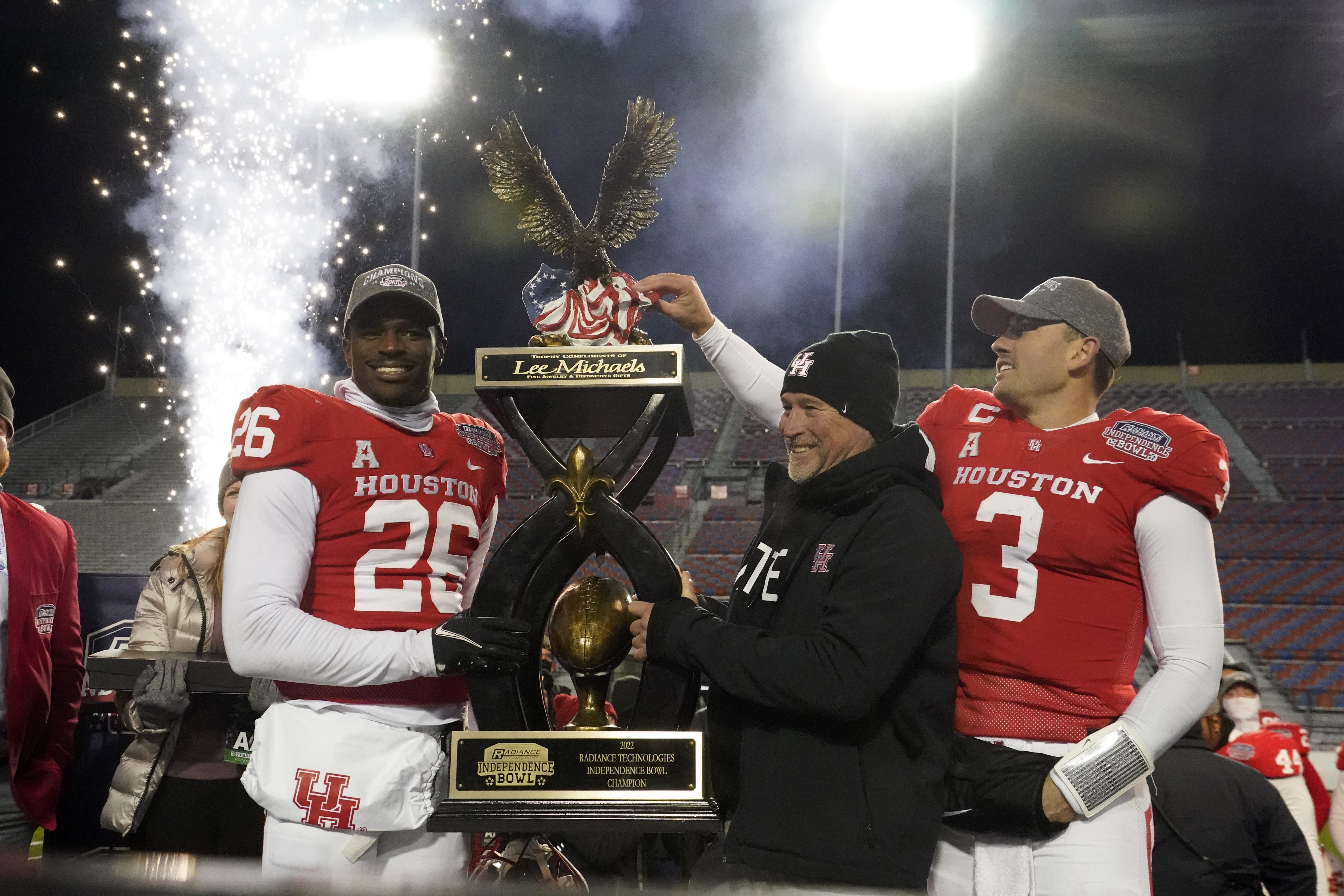 CORRECTS TO ART GREEN NOT MOSES ALEXANDER - Houston head coach Dana Holgorsen, center, looks on as he and defensive back Art Green (26) and quarterback Clayton Tune (3) hoist the Independence Bowl championship trophy following their win over Louisiana-Lafayette in an NCAA college football game Friday, Dec. 23, 2022, in Shreveport, La. 