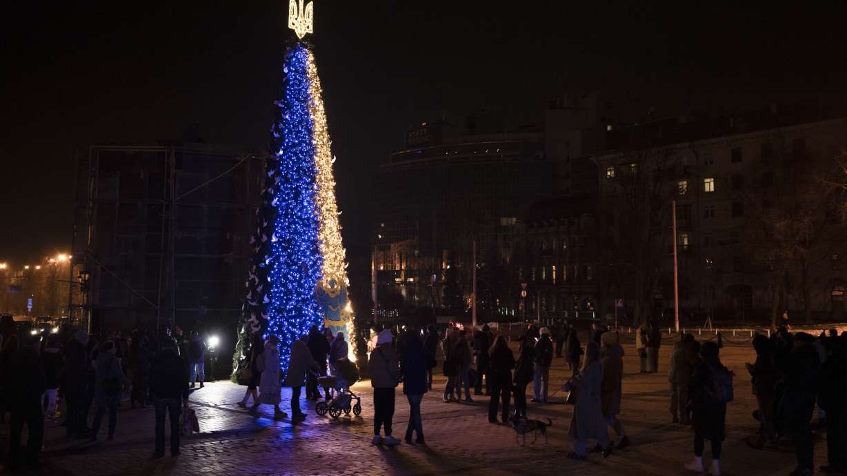 People gather around a Christmas tree decorated with the colors of the Ukrainian national flag at Sophia square in Kyiv, Ukraine, on Friday.
