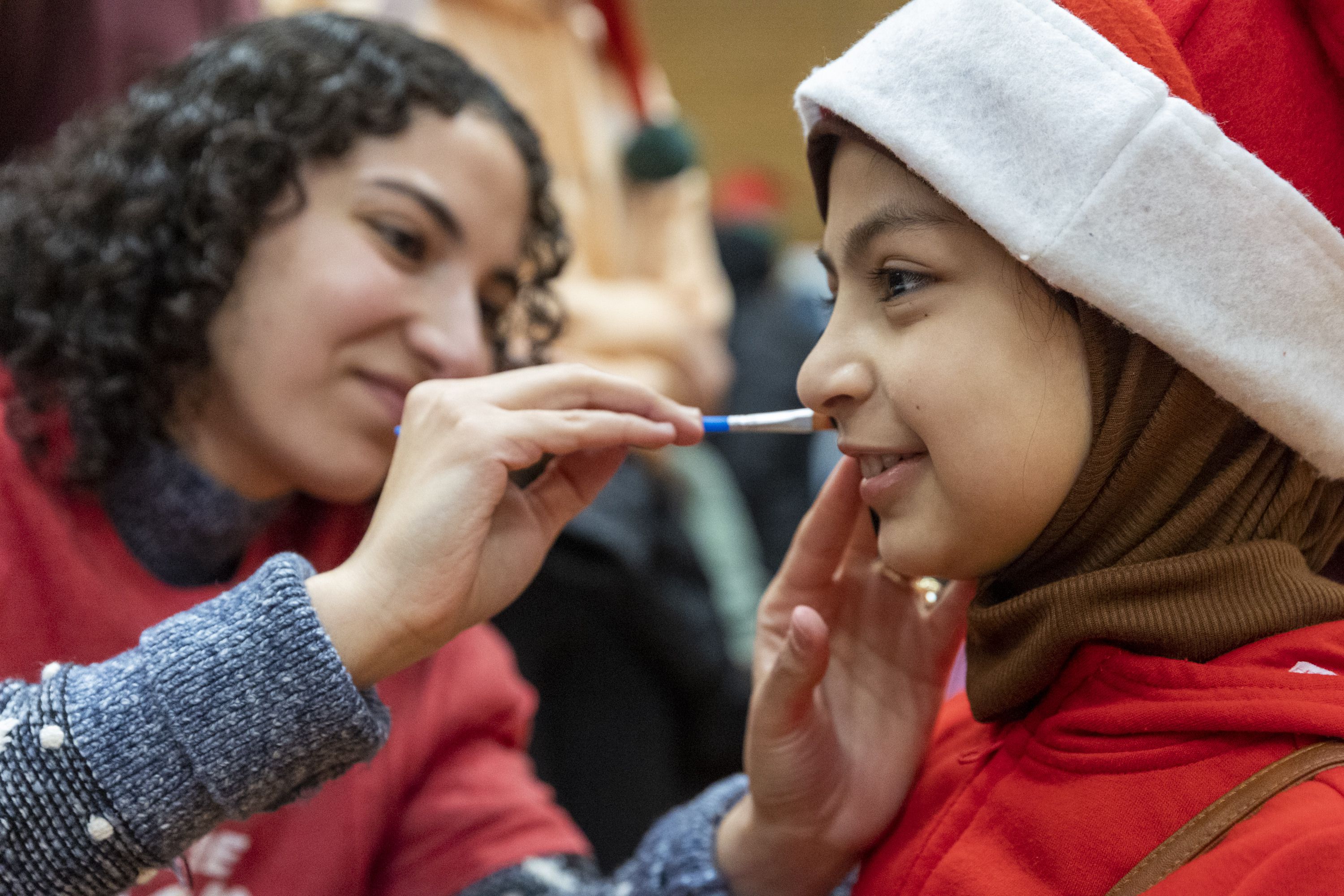 Samar Al Ibrahim paints the face of Zahraa Neamh, 9, at the Utah Refugee Connection “Celebration of Light” at Lincoln Elementary School in South Salt Lake on Saturday, Dec. 17.