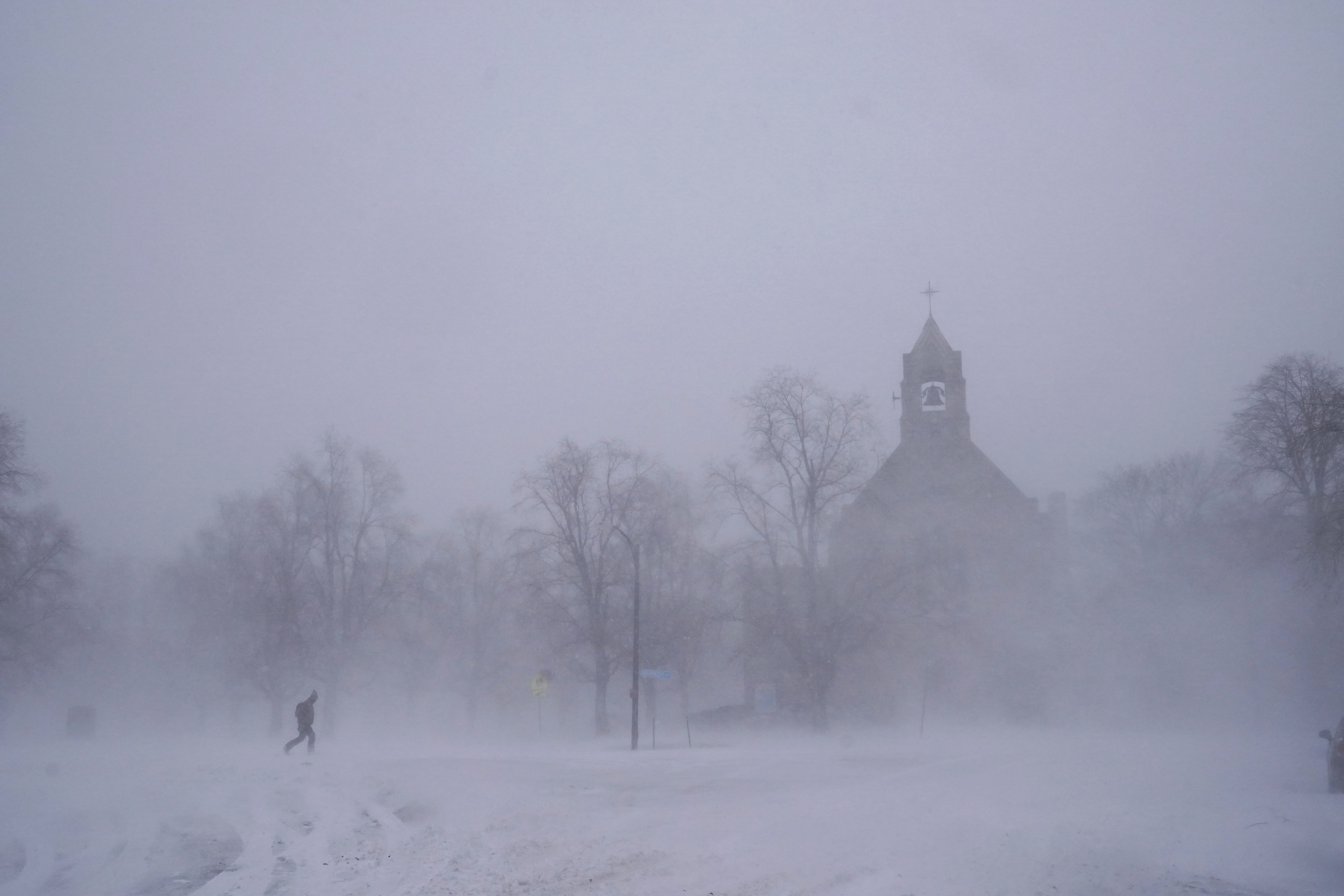 A lone pedestrian in snow shoes makes his way across Colonial Circle as St. John's Grace Episcopal Church rises above the blowing snow amid blizzard conditions in Buffalo, N.Y. on Saturday, Dec. 24.