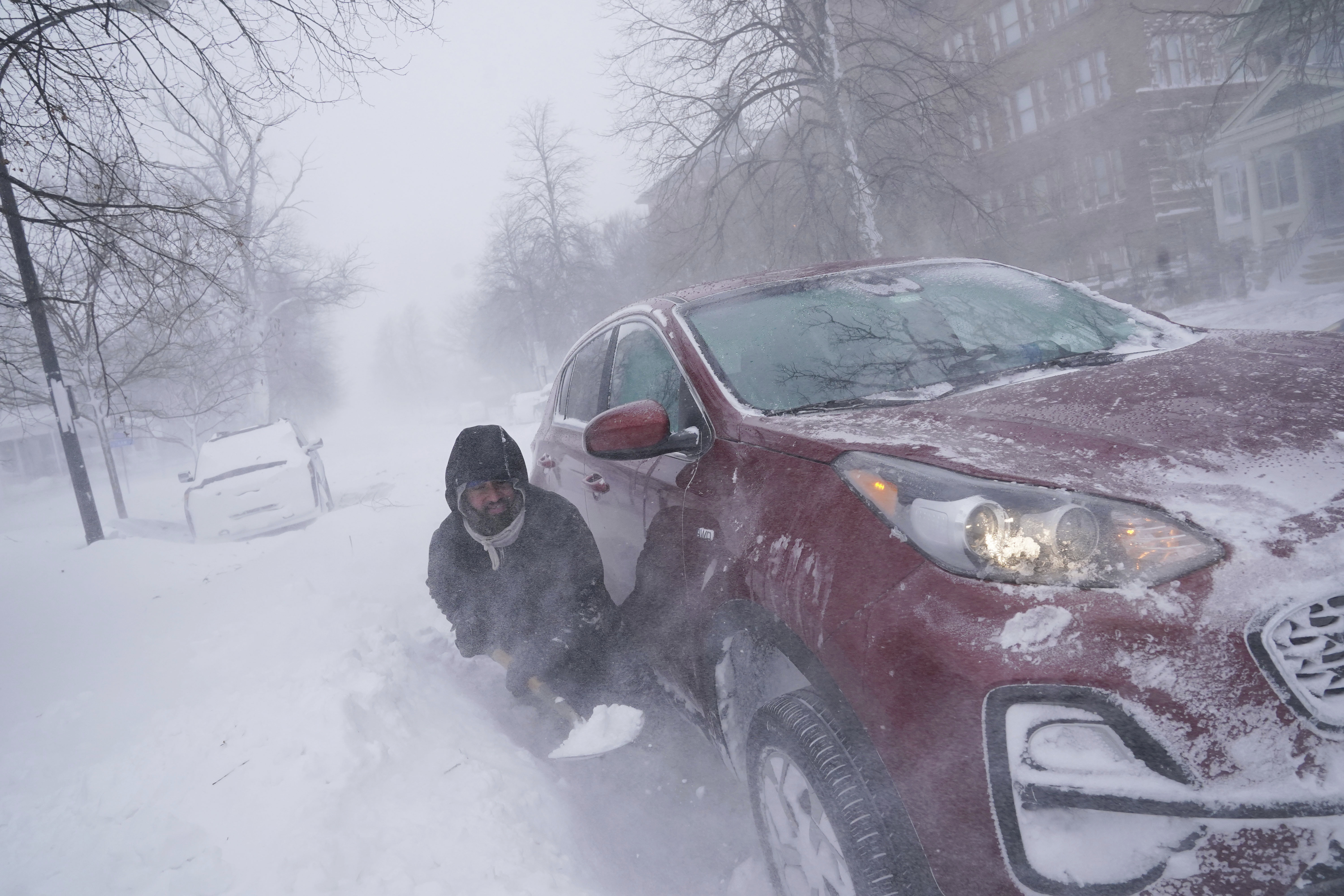 Gamaliel Vega tries to dig out his car on Lafayette Avenue after he got stuck in a snowdrift about a block from home while trying to help rescue his cousin, who had lost power and heat with a baby at home across town during a blizzard in Buffalo, N.Y., on Saturday, Dec. 24.