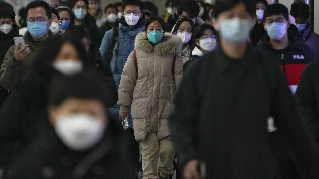 Masked commuters walk through a walkway in between two subway stations as they head to work during the morning rush hour in Beijing, Dec. 20.