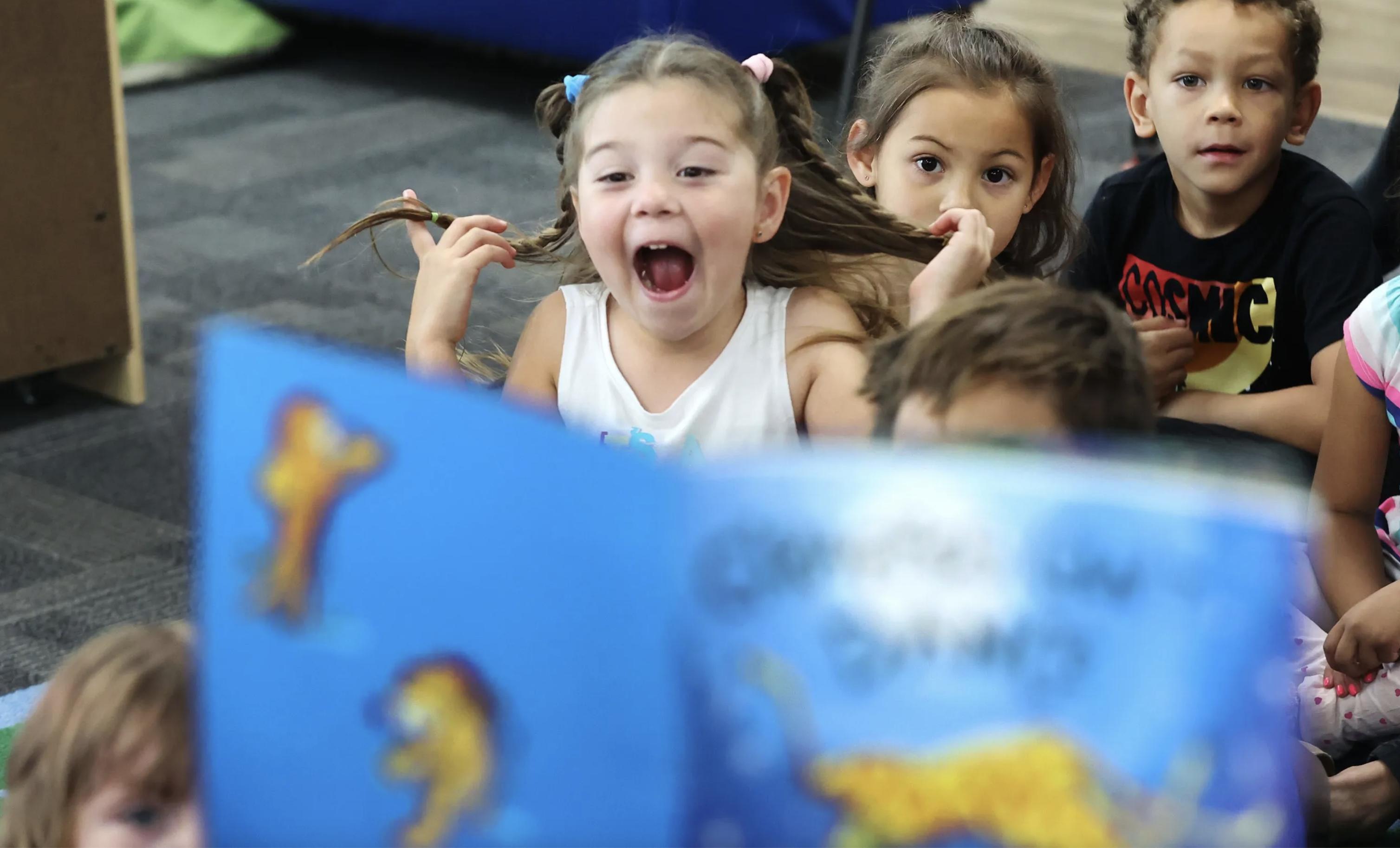 Charlotte, 5, reacts as Lt. Gov. Deidre Henderson reads a book to children at Creative Learning Academy in Salt Lake City on July 12, 2022. A new report released Wednesday shows the significant financial impact child care issues pose on Utah's economy. 