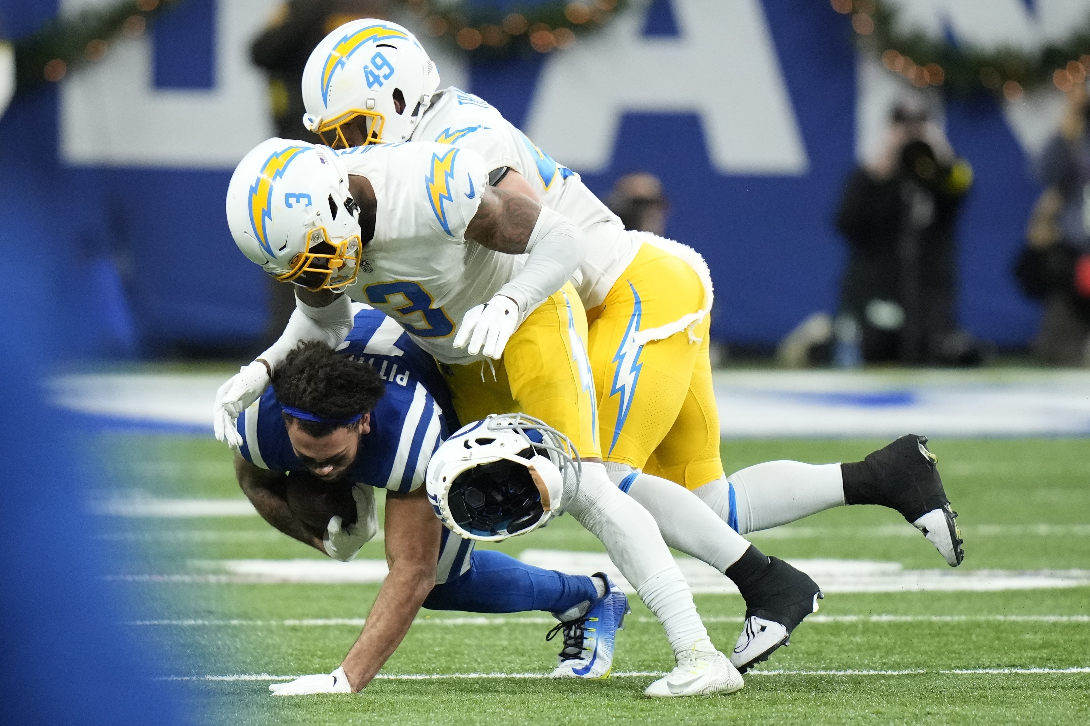 Indianapolis Colts' Michael Pittman Jr. (11) helmet comes off as he is tackled by Los Angeles Chargers' Derwin James Jr. (3) and Drue Tranquill (49) during the first half of an NFL football game, Monday, Dec. 26, 2022, in Indianapolis. 