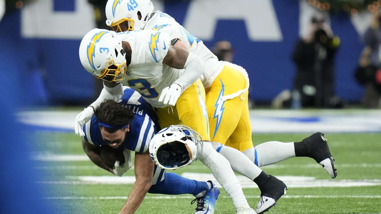 Indianapolis Colts' Michael Pittman Jr. (11) helmet comes off as he is tackled by Los Angeles Chargers' Derwin James Jr. (3) and Drue Tranquill (49) during the first half of an NFL football game, Monday, Dec. 26, 2022, in Indianapolis.