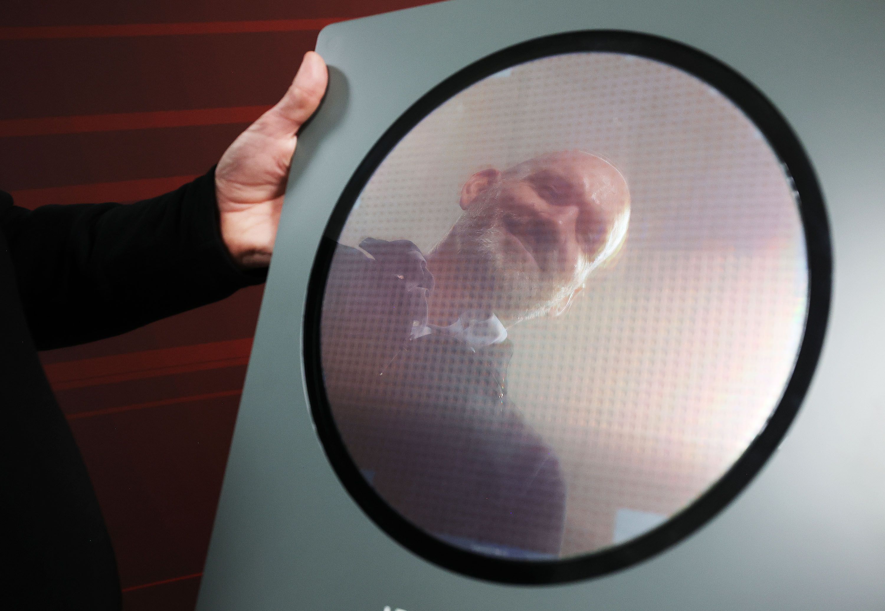 Texas Instruments’ Trevor Bee is reflected in a wafer manufactured at the newly renovated microchip fabrication plant in Lehi on Dec. 14.