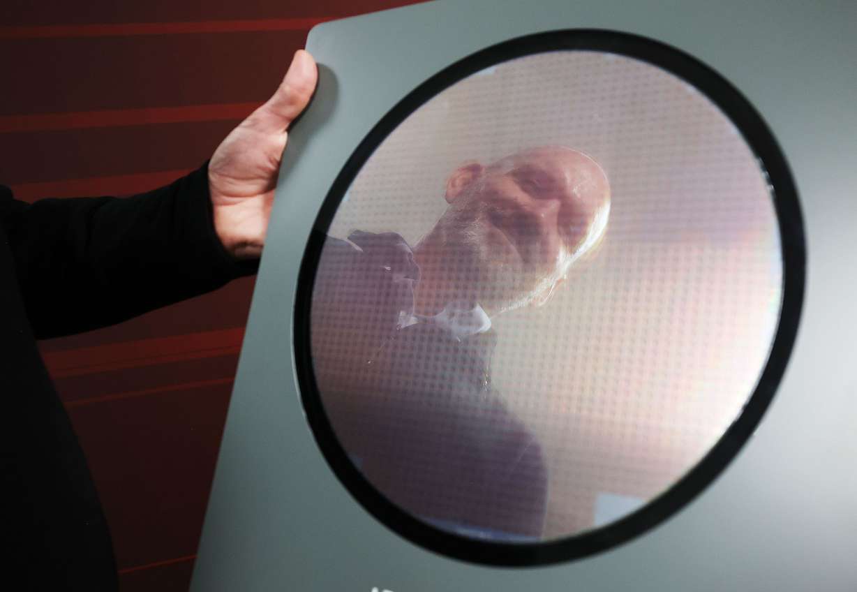Texas Instruments’ Trevor Bee is reflected in a wafer manufactured at the newly renovated microchip fabrication plant in Lehi on Dec. 14.