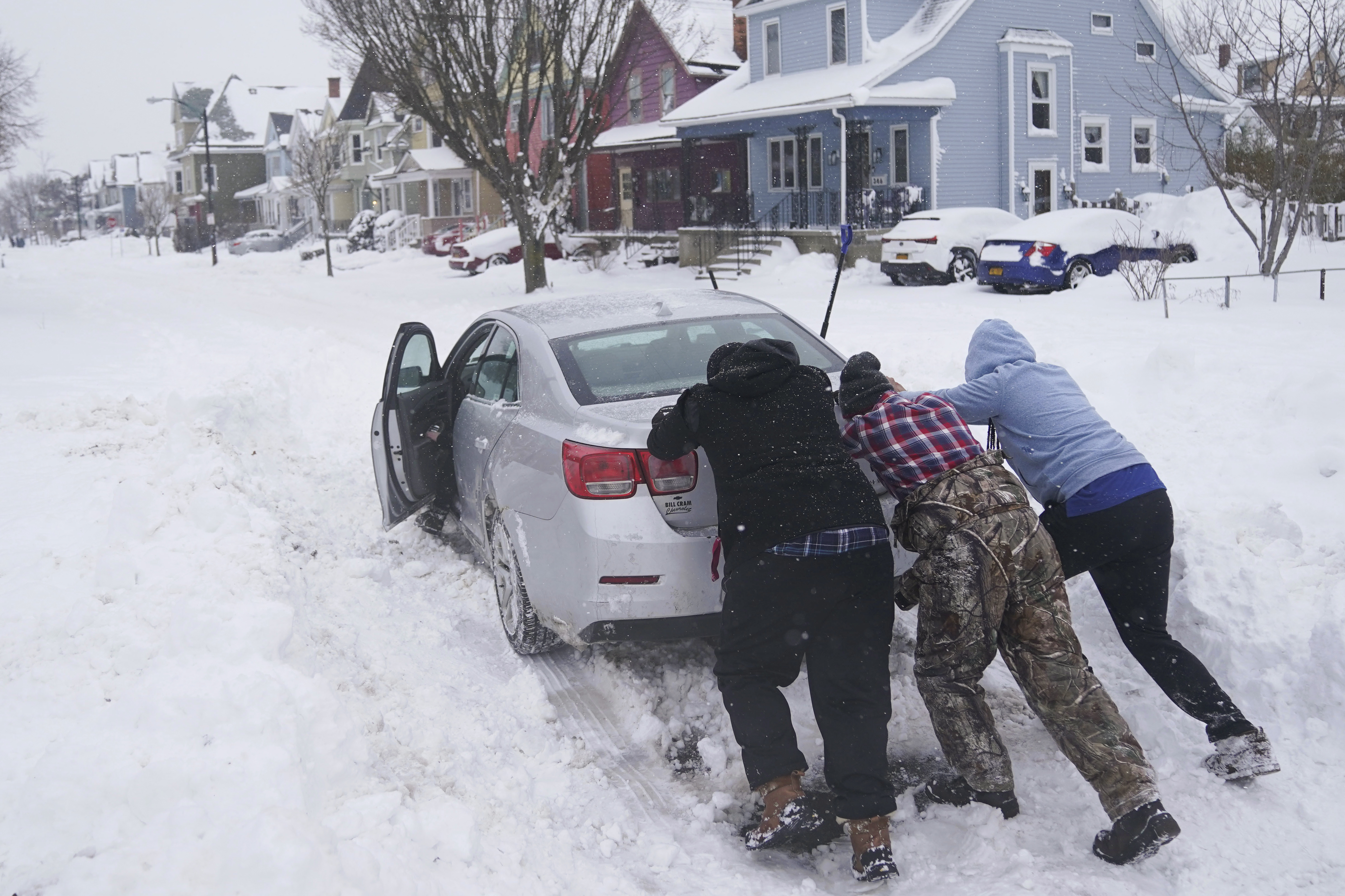 Neighbors help push a motorist stuck in the snow in Buffalo, N.Y., on Monday.