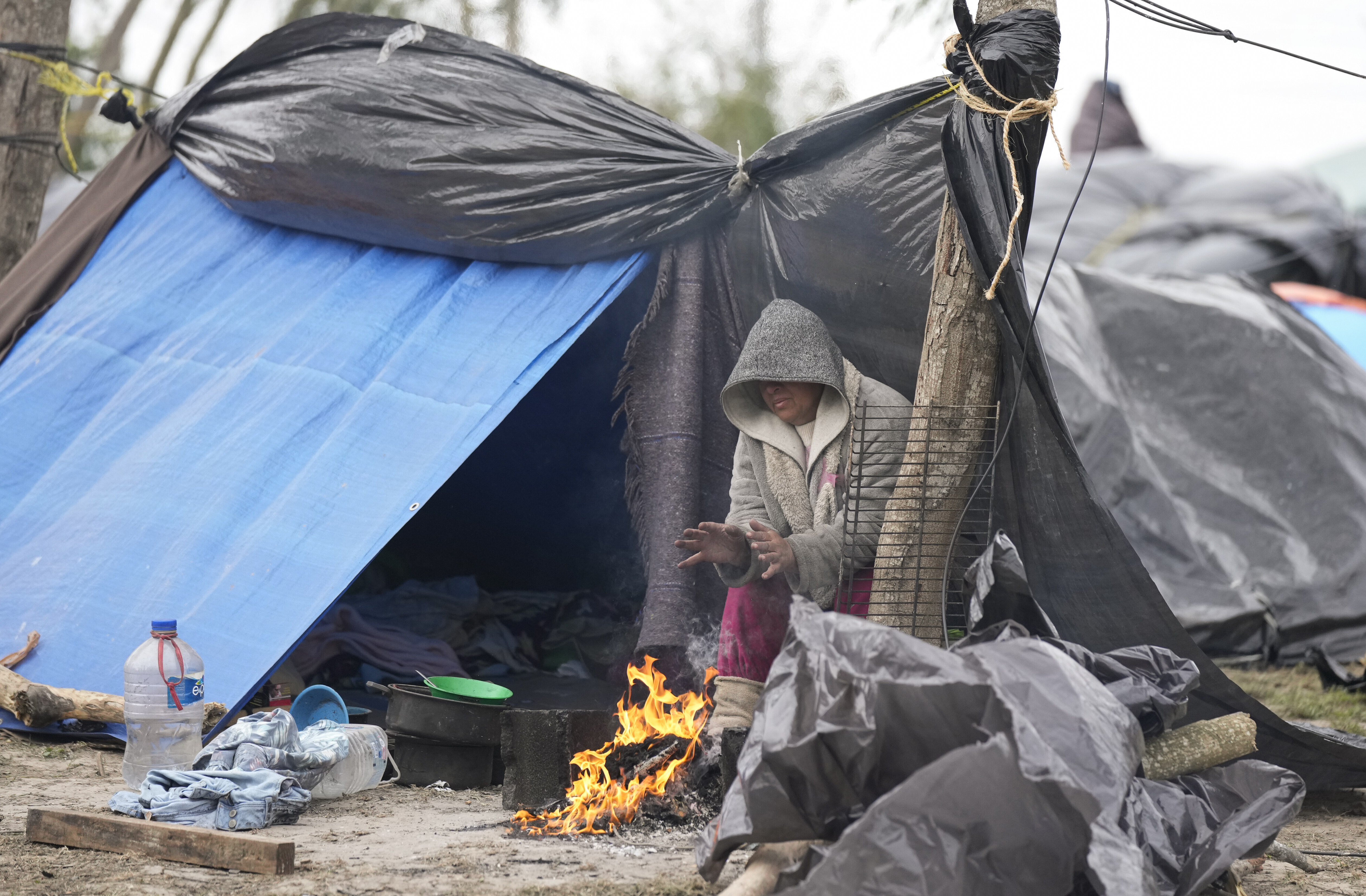 A Venezuelan migrant warms her hands over a campfire outside her makeshift tent refusing to be relocated to a refugee shelter, in Matamoros, Mexico, Dec. 23. Migrants are waiting along the U.S.-Mexico border on a pending U.S. Supreme Court decision on asylum restrictions. 