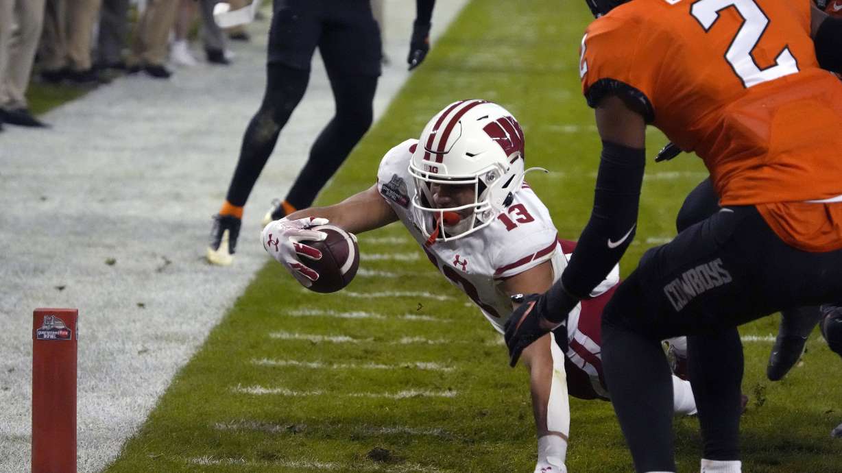 Wisconsin wide receiver Chimere Dike dives for the end zone in front of Oklahoma State cornerback Korie Black (2) during the first half of the Guaranteed Rate Bowl NCAA college football game Tuesday, Dec. 27, 2022, in Phoenix.