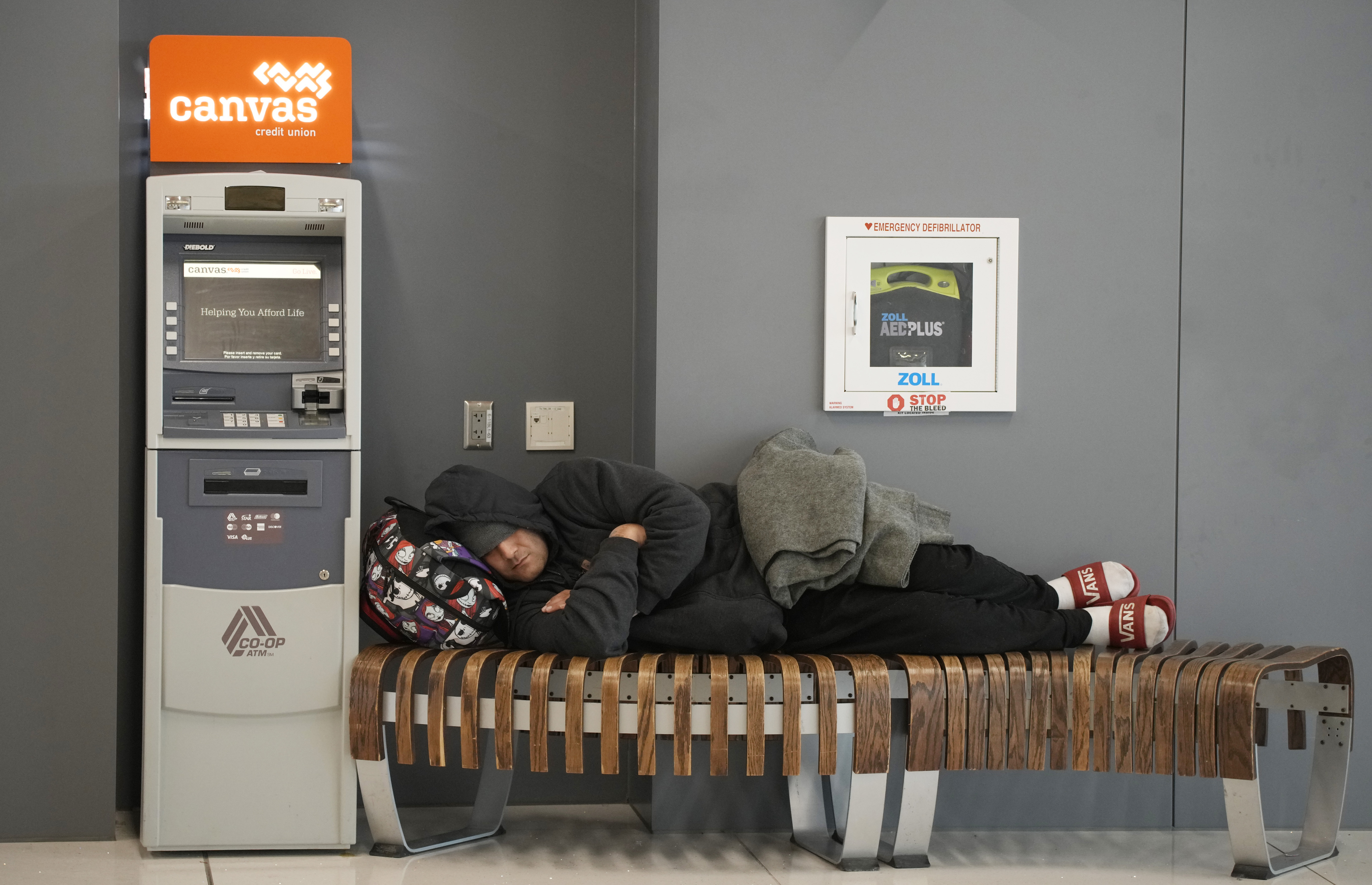 A traveler sleeps on a bench near the Southwest Airlines check-in counter at Denver International Airport, Tuesday, in Denver.