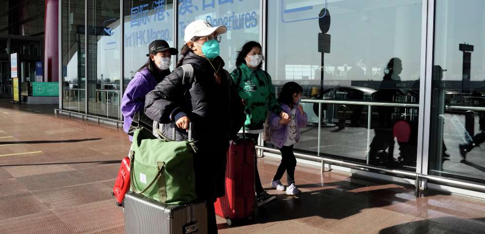 Passengers wearing masks walk through the Capital airport terminal in Beijing on Dec. 13. On Wednesday the U.S. announced new COVID-19 testing requirements for all travelers from China, joining other nations imposing restrictions because of a surge of infections.