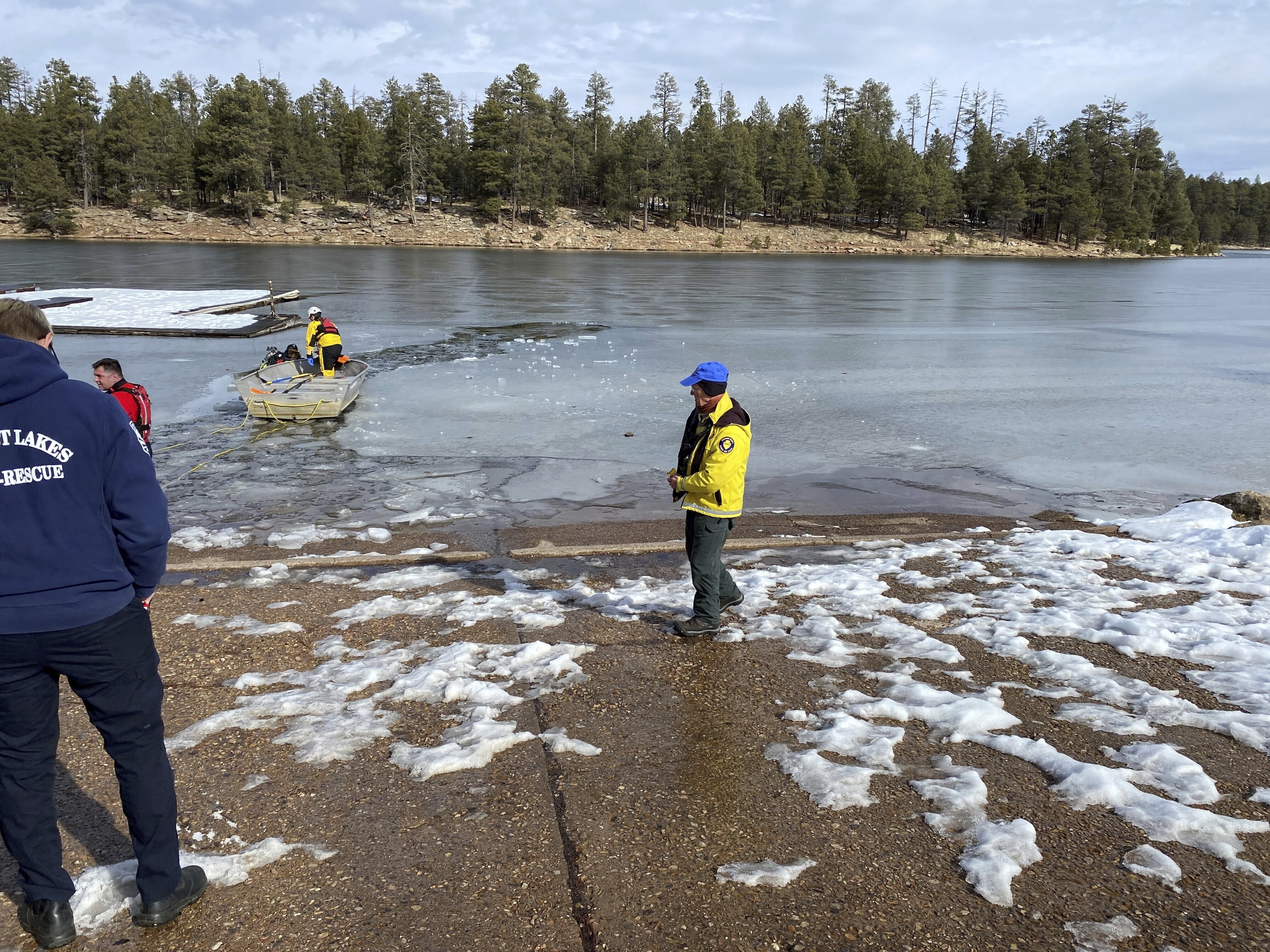In this image provided by the Coconino County, Ariz., Sheriff's Office, a search team works to recover two of three people who drowned after they fell through the ice at Woods Canyon Lake in Forest Lakes, Ariz., on Tuesday.