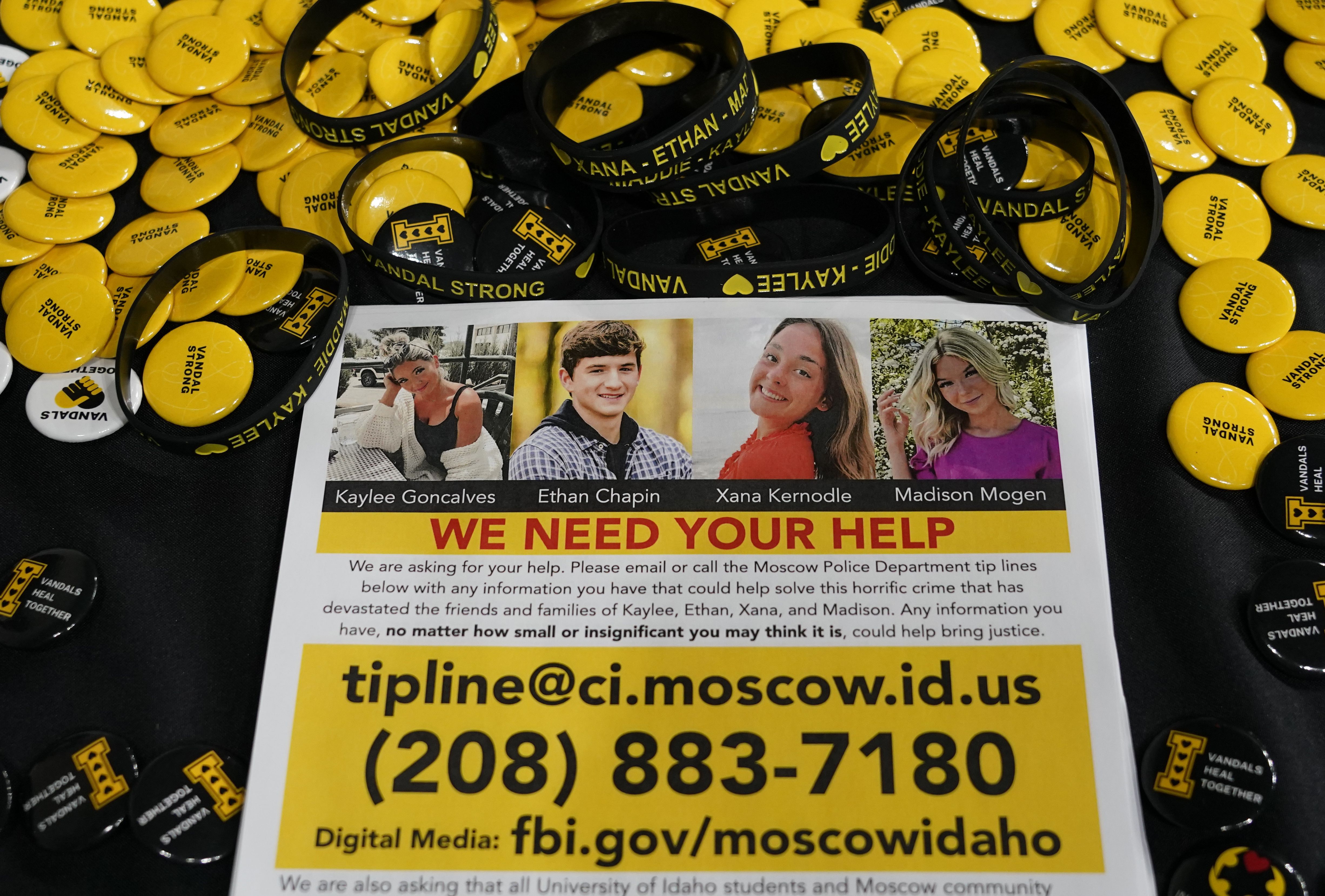A flyer seeking information about the killings of four University of Idaho students who were found dead is displayed on a table along with buttons and bracelets on Nov. 30 during a vigil in memory of the victims in Moscow, Idaho.