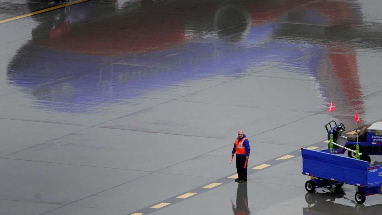A Southwest Airlines ground operations crew member waits to guide an arriving jet into a gate, Wednesday, at Sky Harbor International Airport in Phoenix.