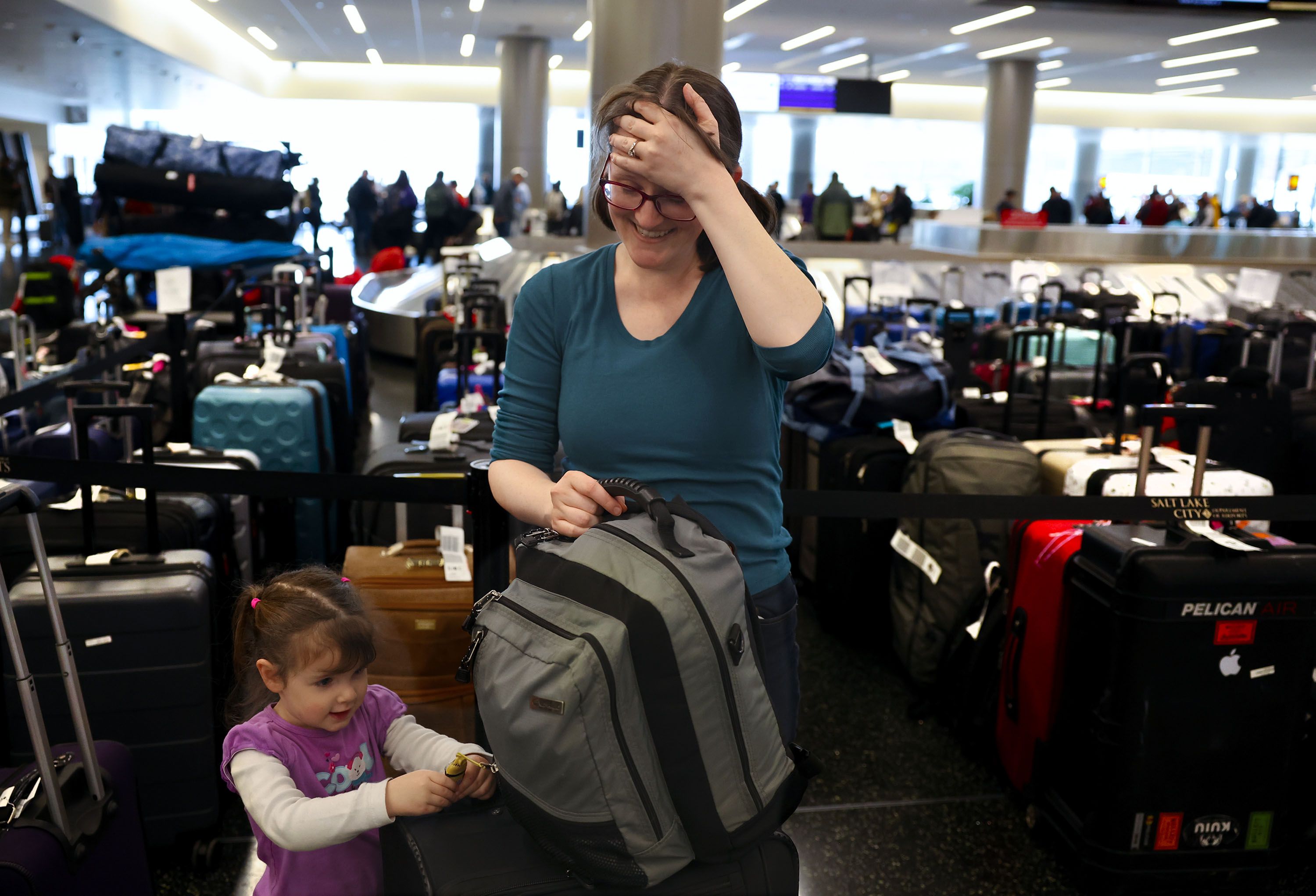 Casandra Friend, of Provo, laughs as her daughter asks for a toy after collecting their luggage at the Southwest luggage carousel at the Salt Lake City International Airport in Salt Lake City on Friday.