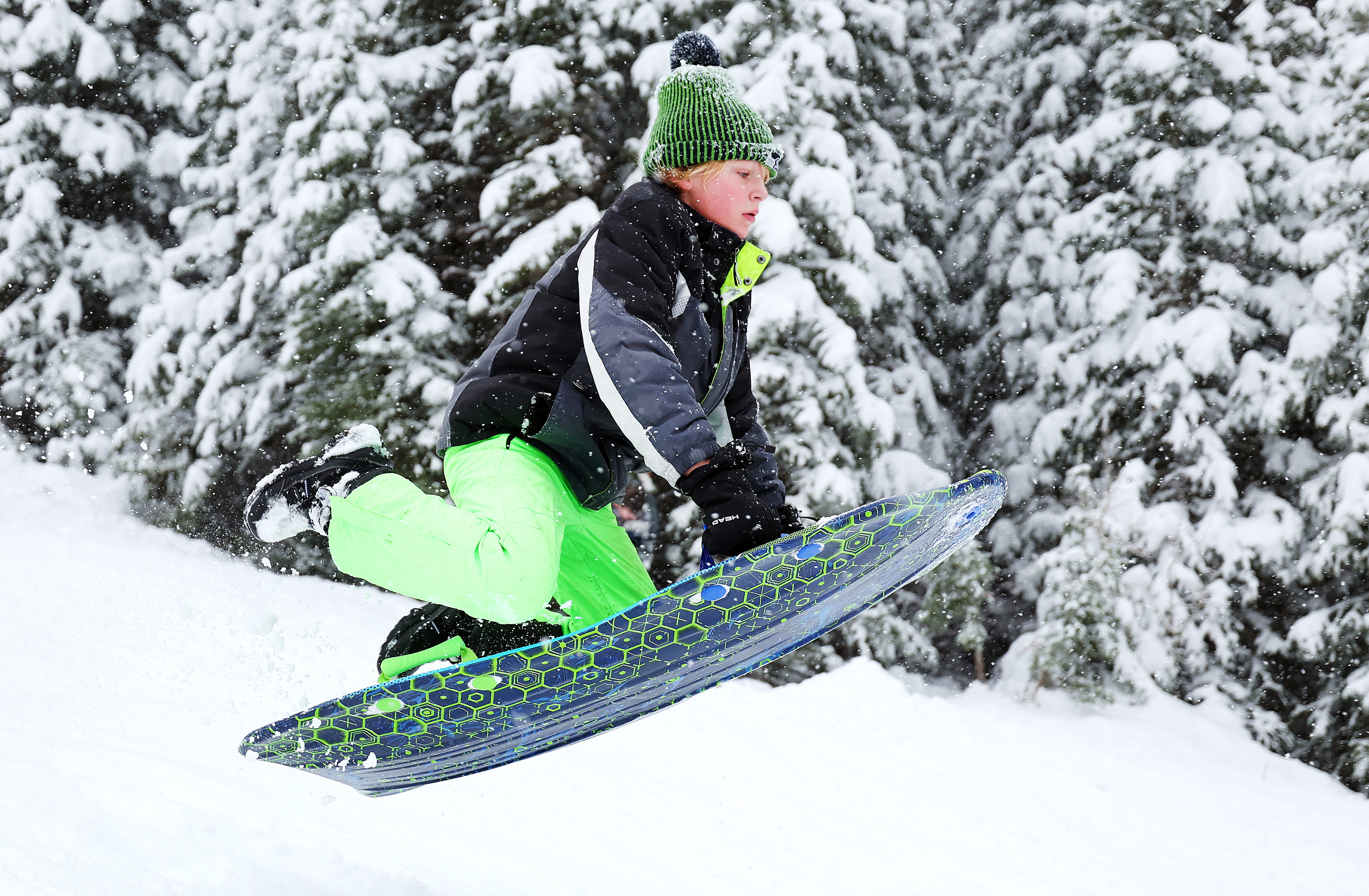 Micah Warr jumps into the air as he and other sledders enjoy the snow falling in Big Cottonwood Canyon on Friday.