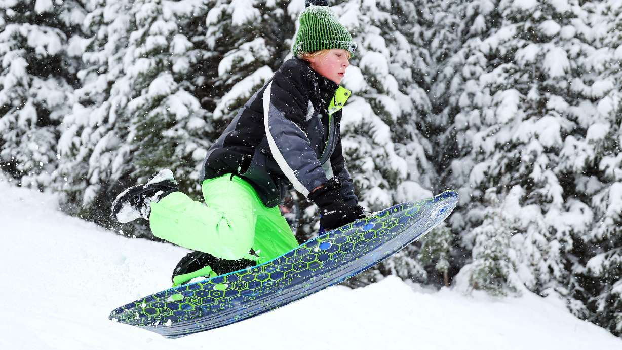 Micah Warr jumps into the air as he and other sledders enjoy the snow falling in Big Cottonwood Canyon on Friday.
