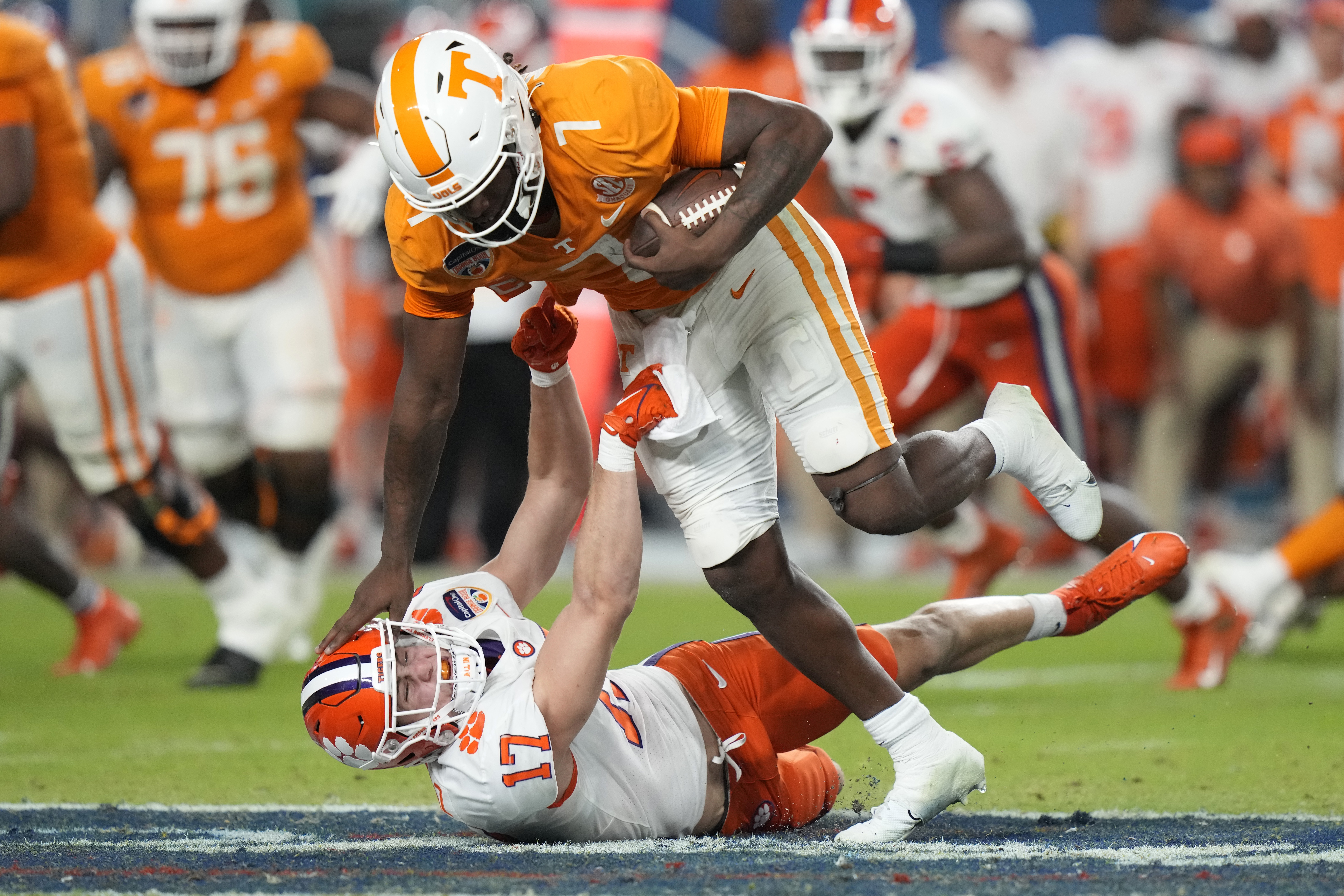 Tennessee quarterback Joe Milton III (7) runs as Clemson linebacker Wade Woodaz (17) attempts a tackle during the first half of the Orange Bowl NCAA college football game Friday, Dec. 30, 2022, in Miami Gardens, Fla. 