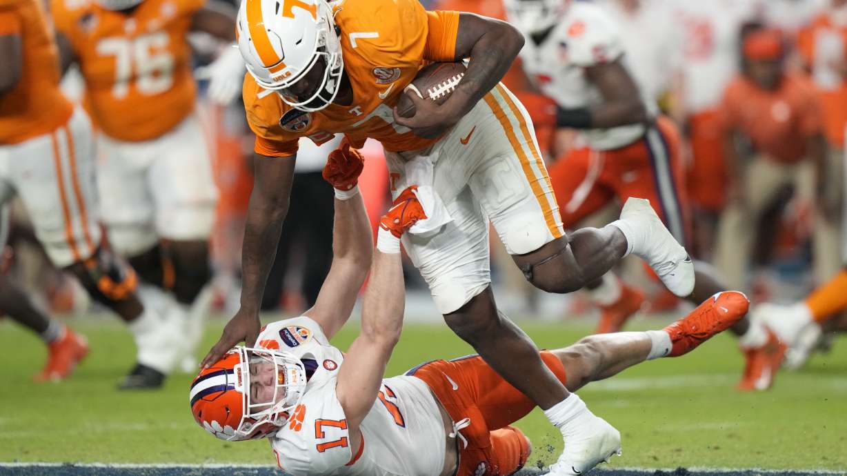 Tennessee quarterback Joe Milton III (7) runs as Clemson linebacker Wade Woodaz (17) attempts a tackle during the first half of the Orange Bowl NCAA college football game Friday, Dec. 30, 2022, in Miami Gardens, Fla.