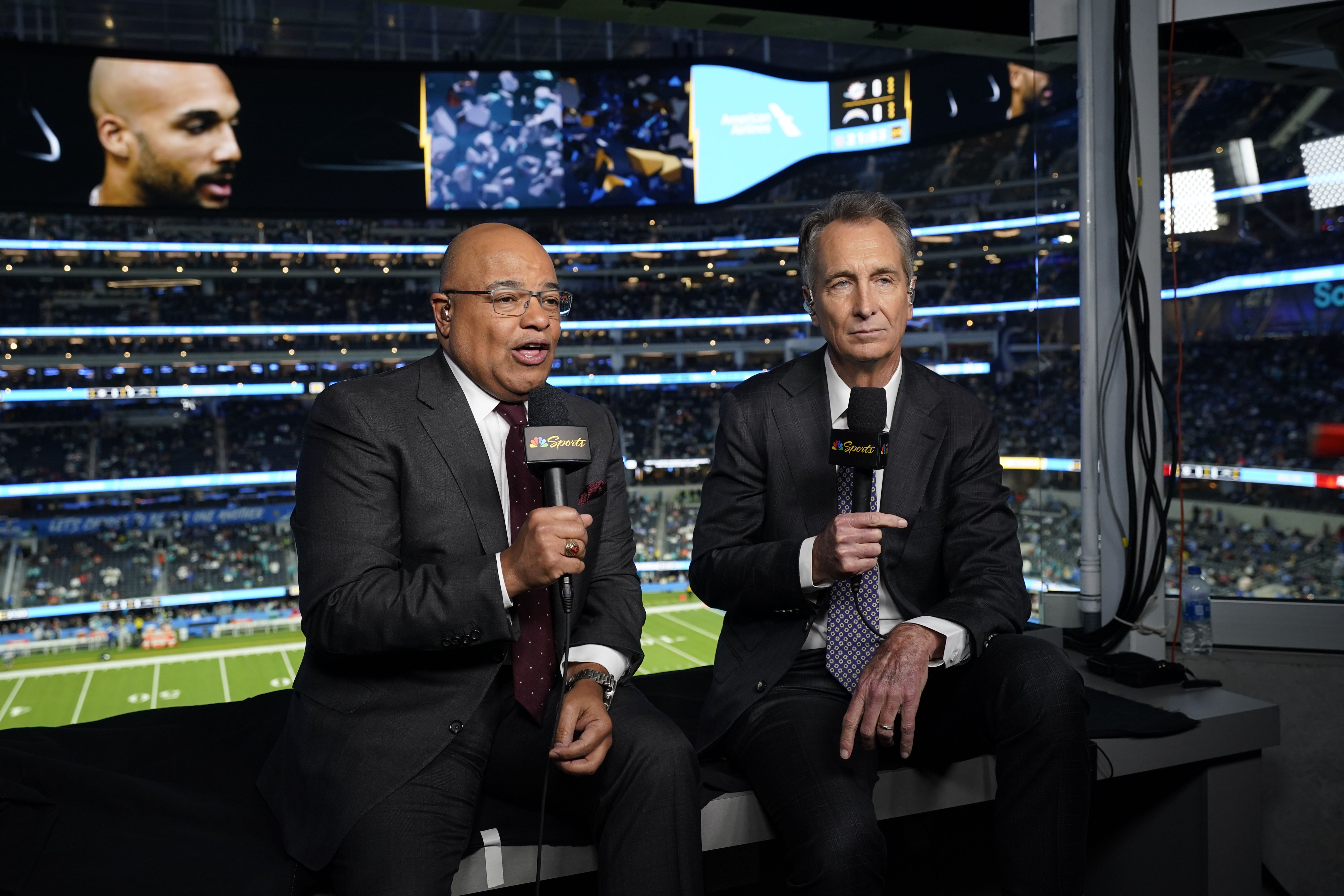 NBC Sports play-by-play announcer Mike Tirico, left, sits next to color commentator Cris Collinsworth before an NFL football game between the Los Angeles Chargers and the Miami Dolphins on Dec. 11, 2022, in Inglewood, Calif.
