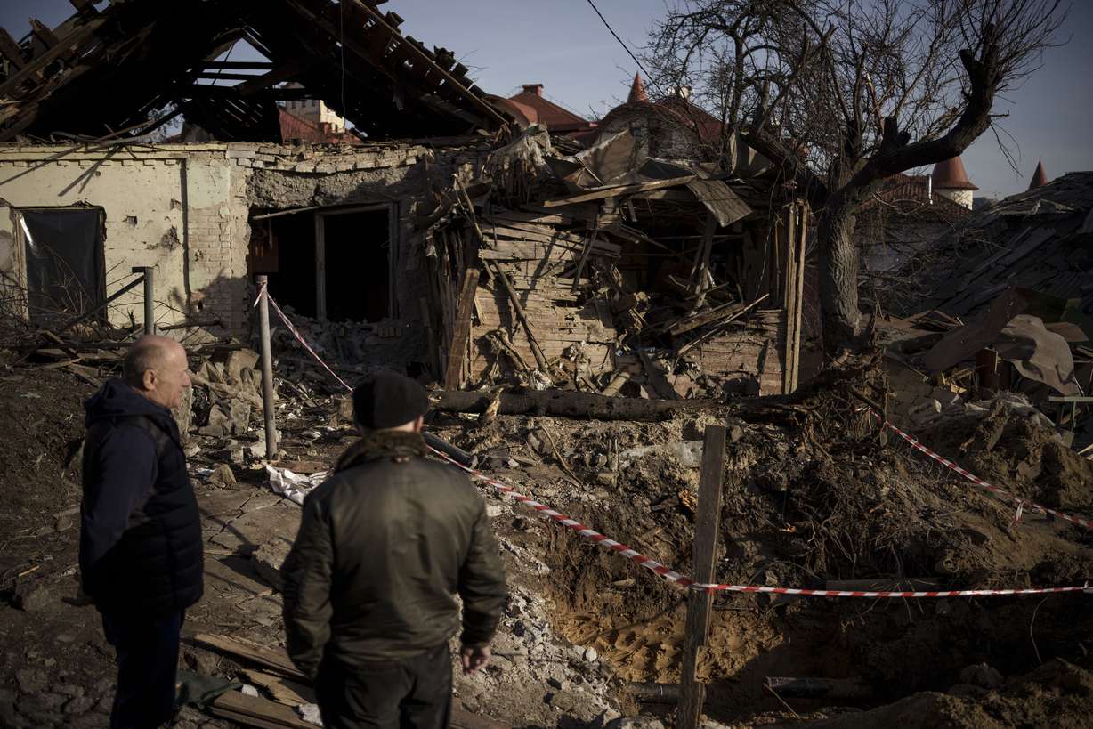 People stand next to the site of a Russian attack in Kyiv, Ukraine, Monday.