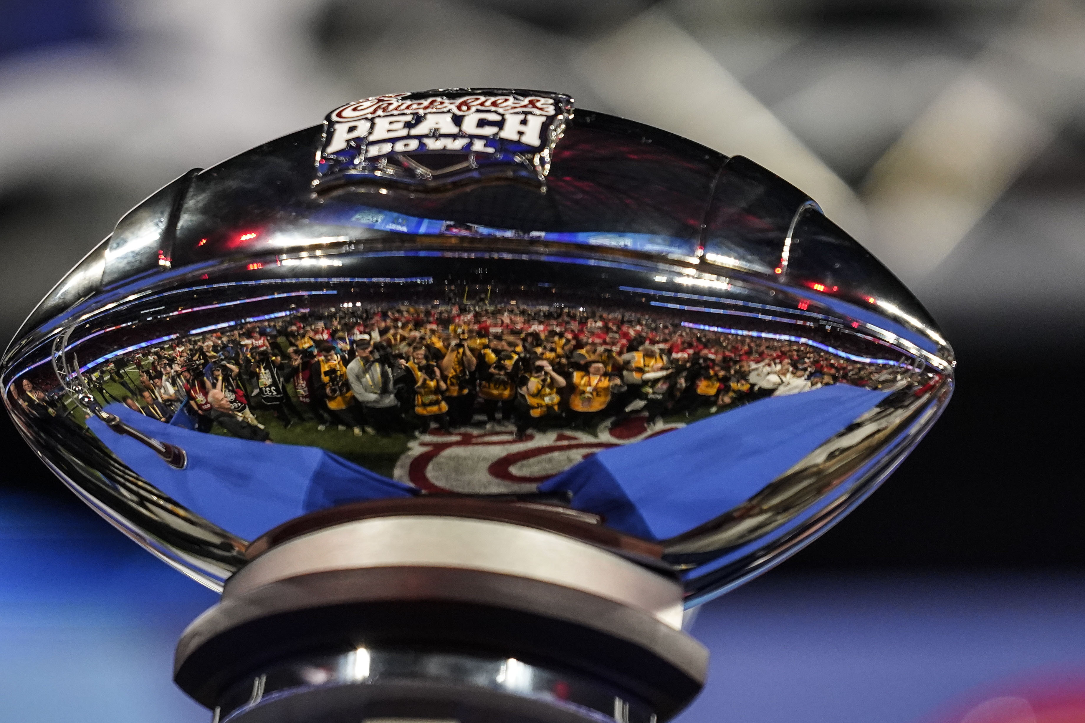 Photographers are reflected in the The George P. Crumbley Trophy after the Peach Bowl NCAA college football semifinal playoff game between Georgia and Ohio State, Sunday, Jan. 1, 2023, in Atlanta. Georgia won 42-41. 