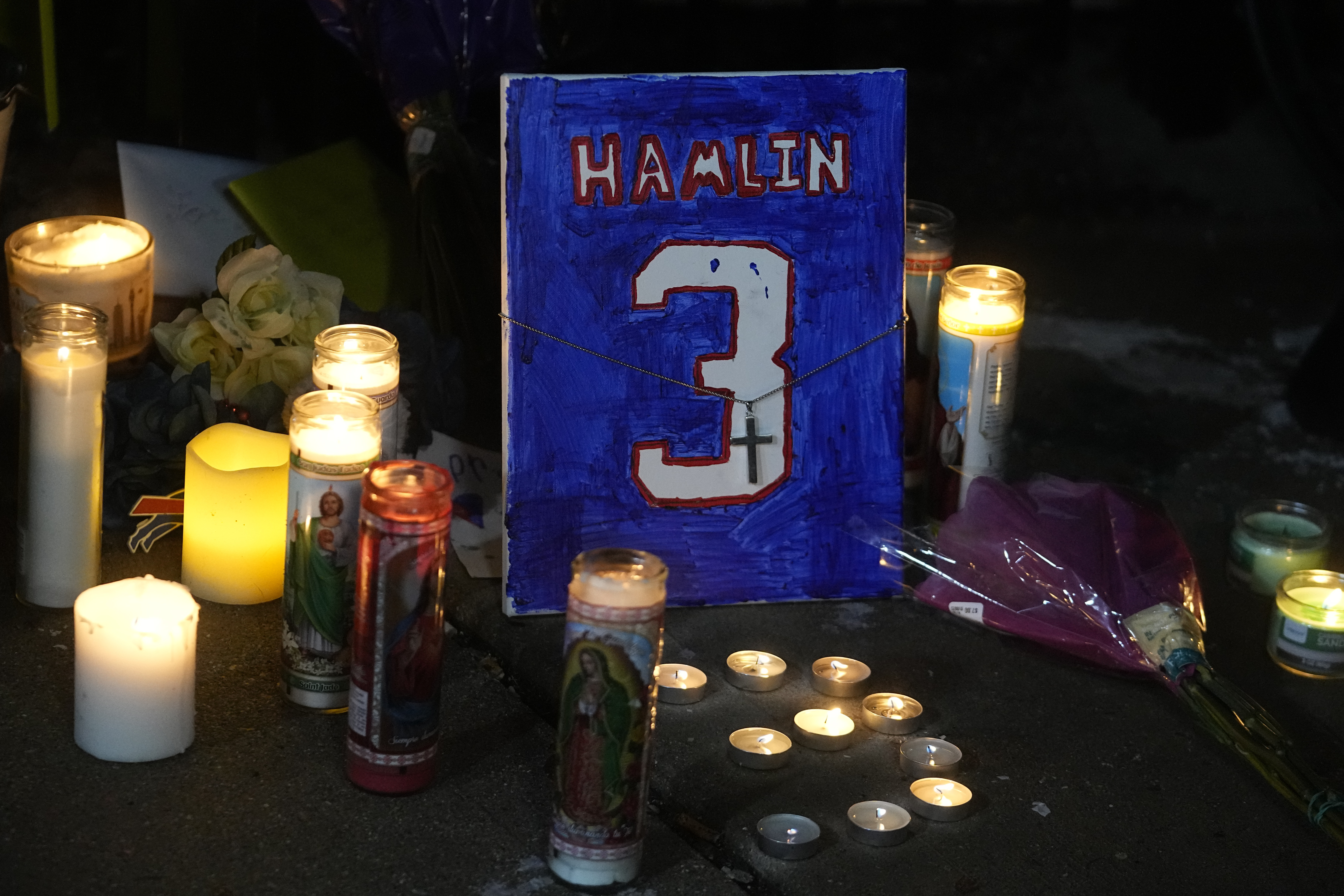A painting that shows the number of Buffalo Bills' Damar Hamlin is illuminated by candles during a prayer vigil outside University of Cincinnati Medical Center, Tuesday, in Cincinnati. Hamlin's recovery is moving in "a positive direction," a representative said Wednesday.