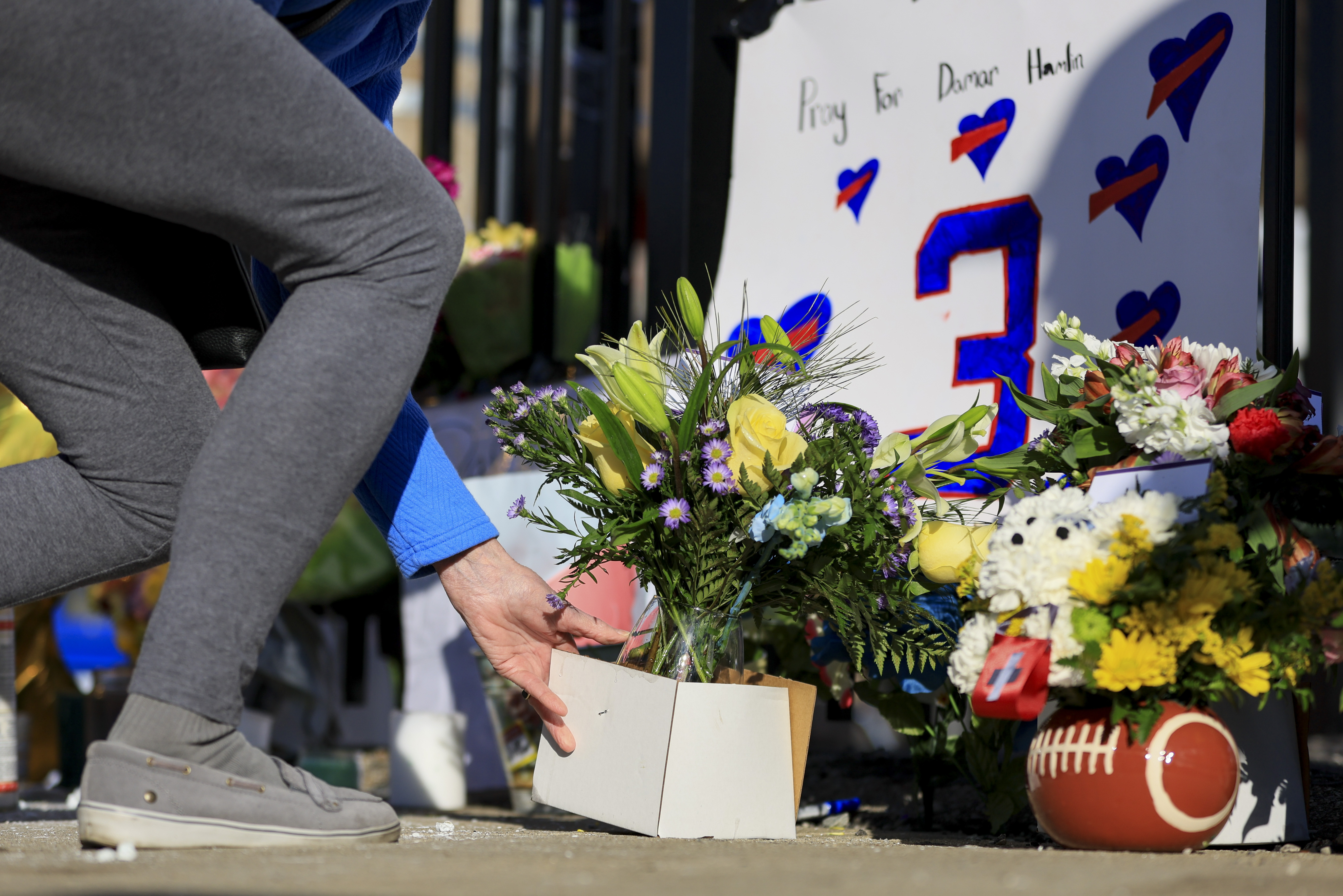 A person leaves flowers for the display set-up for Buffalo Bills' Damar Hamlin outside of University of Cincinnati Medical Center, Wednesday, Jan. 4, 2023, in Cincinnati. Hamlin was taken to the hospital after collapsing on the field during the Bill's NFL football game against the Cincinnati Bengals on Monday night.
