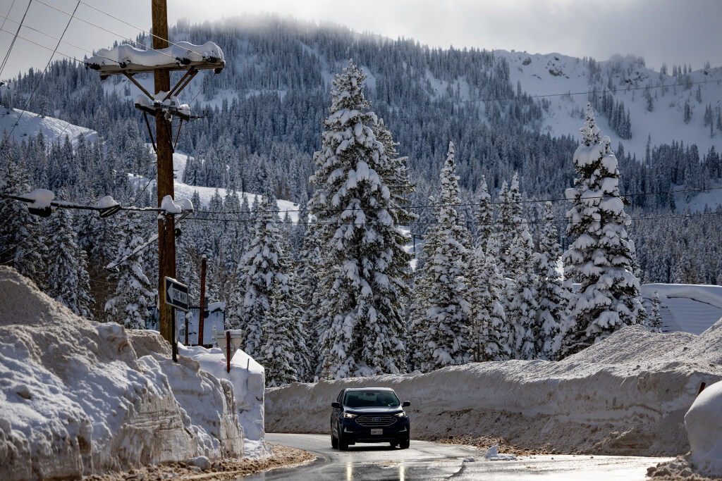 Snowbanks tower over a car driving in the town of Brighton on Jan. 4. A man was killed in a roof avalanche in Brighton on Monday.