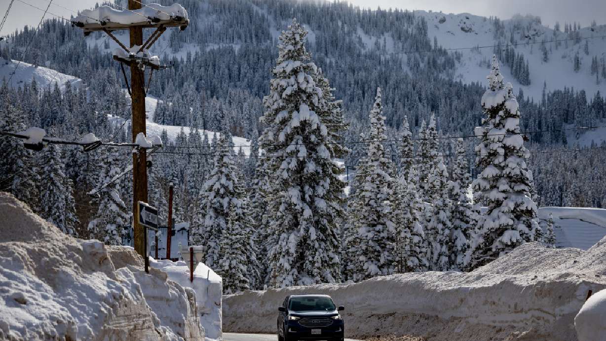 Snowbanks tower over a car driving in the town of Brighton on Jan. 4. A man was killed in a roof avalanche in Brighton on Monday.