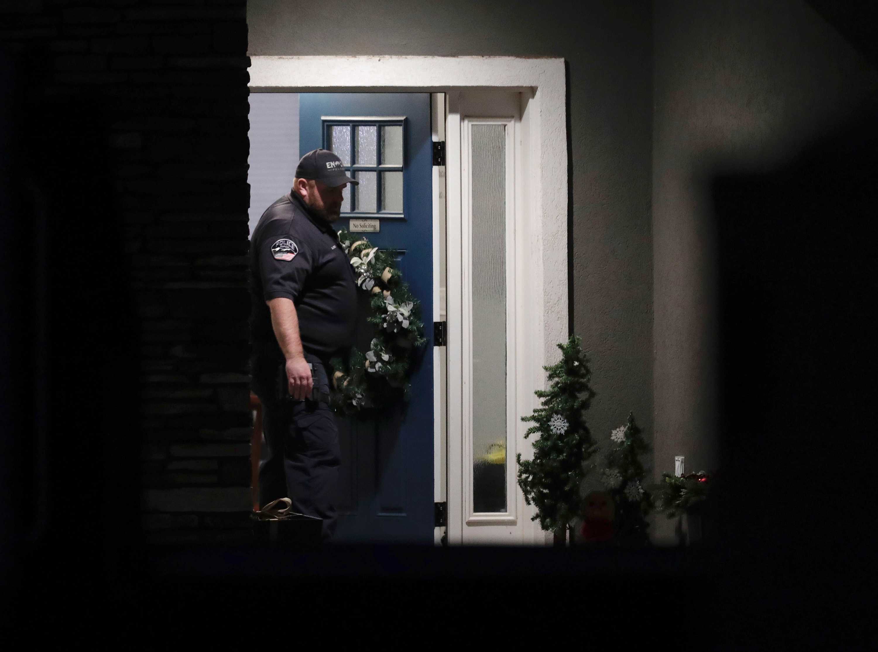 A law enforcement official stands at the front door of the Enoch home where eight family members were found shot to death Wednesday.