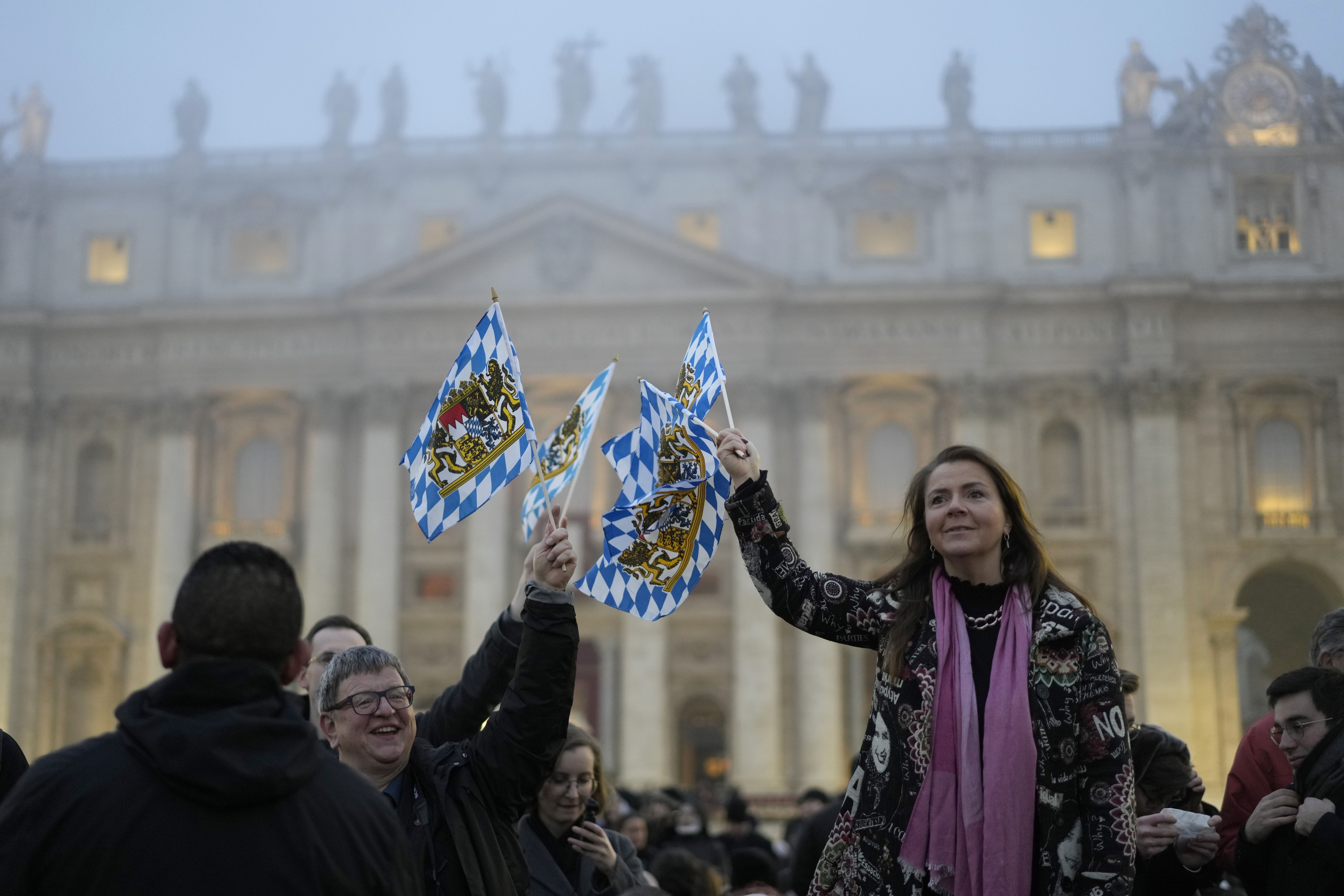 People wave Bavarian flags while waiting for the funeral mass for late Pope Emeritus Benedict XVI in St. Peter's Square at the Vatican, Thursday.