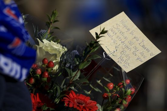 Carol Smith carries flowers for the display set-up for Buffalo Bills' Damar Hamlin outside of University of Cincinnati Medical Center, Wednesday in Cincinnati. Hamlin was taken to the hospital after collapsing on the field during the Bill's NFL football game against the Cincinnati Bengals on Monday night.