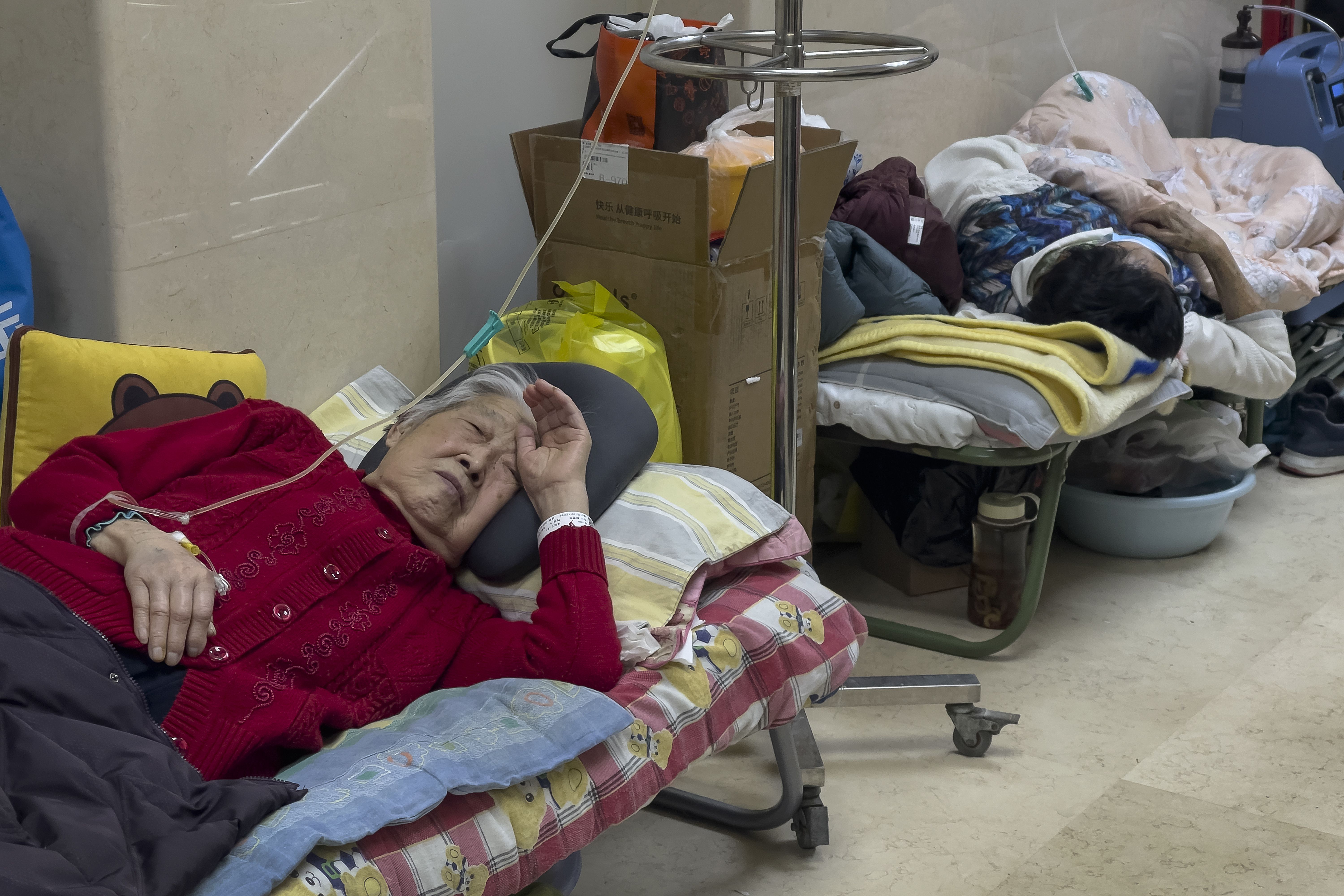 Elderly patients rest along a corridor of the emergency ward as they receive intravenous drips in Beijing, Thursday. Patients, most of them elderly, are lying on stretchers in hallways and taking oxygen while sitting in wheelchairs as COVID-19 surges in China’s capital Beijing.