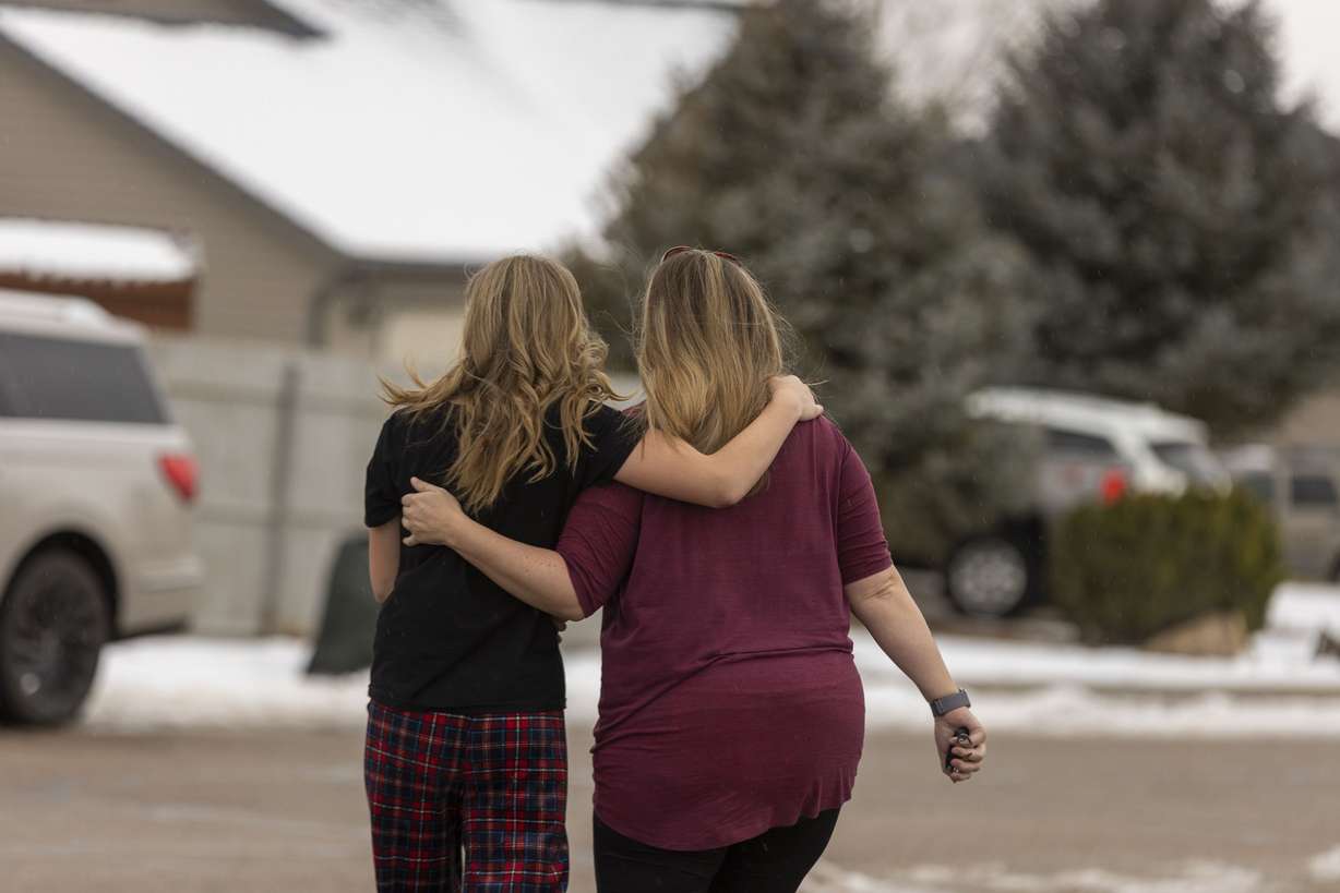 Community members on Thursday walk away from a memorial that was created outside of a home in Enoch, Iron County, where police say 42-year-old Michael Haight killed his wife, Tausha Haight, 40, and Tausha’s mother, 78-year-old Gail Earl, and his five children — a 17-year-old female, 12-year-old female, 7-year-old female, 7-year-old male, and a 4-year-old male — before taking his own life.