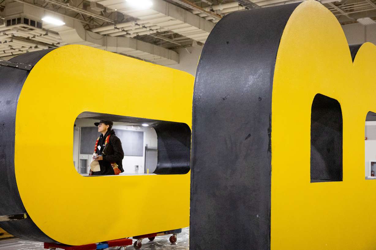 Destinie Ostler, who works for tradeshow services company Freeman, walks past large “OR” signage being prepared for the Outdoor Retailer show at the Salt Palace Convention Center in Salt Lake City on Thursday.
