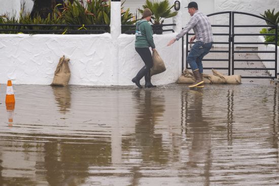 The owners of Venus Pie Trap place sandbags in front of their restaurant in the Rio Del Mar neighborhood of Aptos, Calif., Monday.