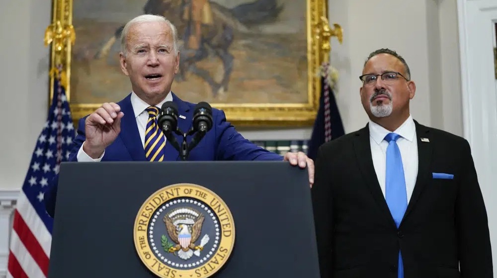 President Joe Biden speaks about student loan debt forgiveness in the Roosevelt Room of the White House, on Aug. 24, 2022, in Washington. Education Secretary Miguel Cardona listens at right. The White House is moving forward with a proposal to repay federal loans under far more generous terms.